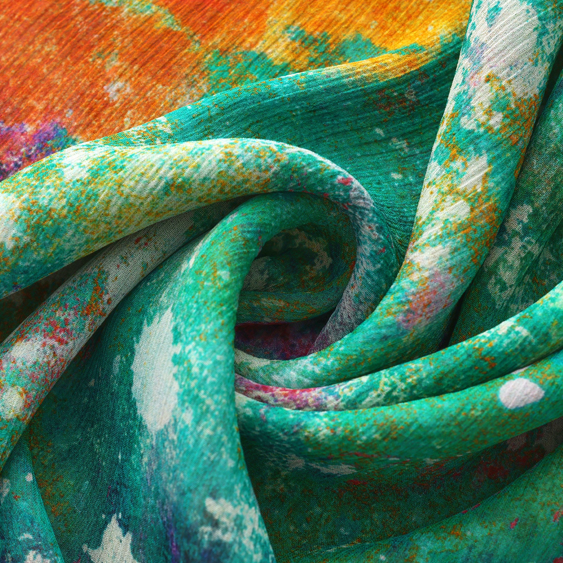 A close-up of colorful, textured fabric with swirling folds. The Natural Silk Scarf Mundos Ocultos showcases vibrant green, orange, yellow, and white in a dynamic abstract pattern—a true piece of wearable art.