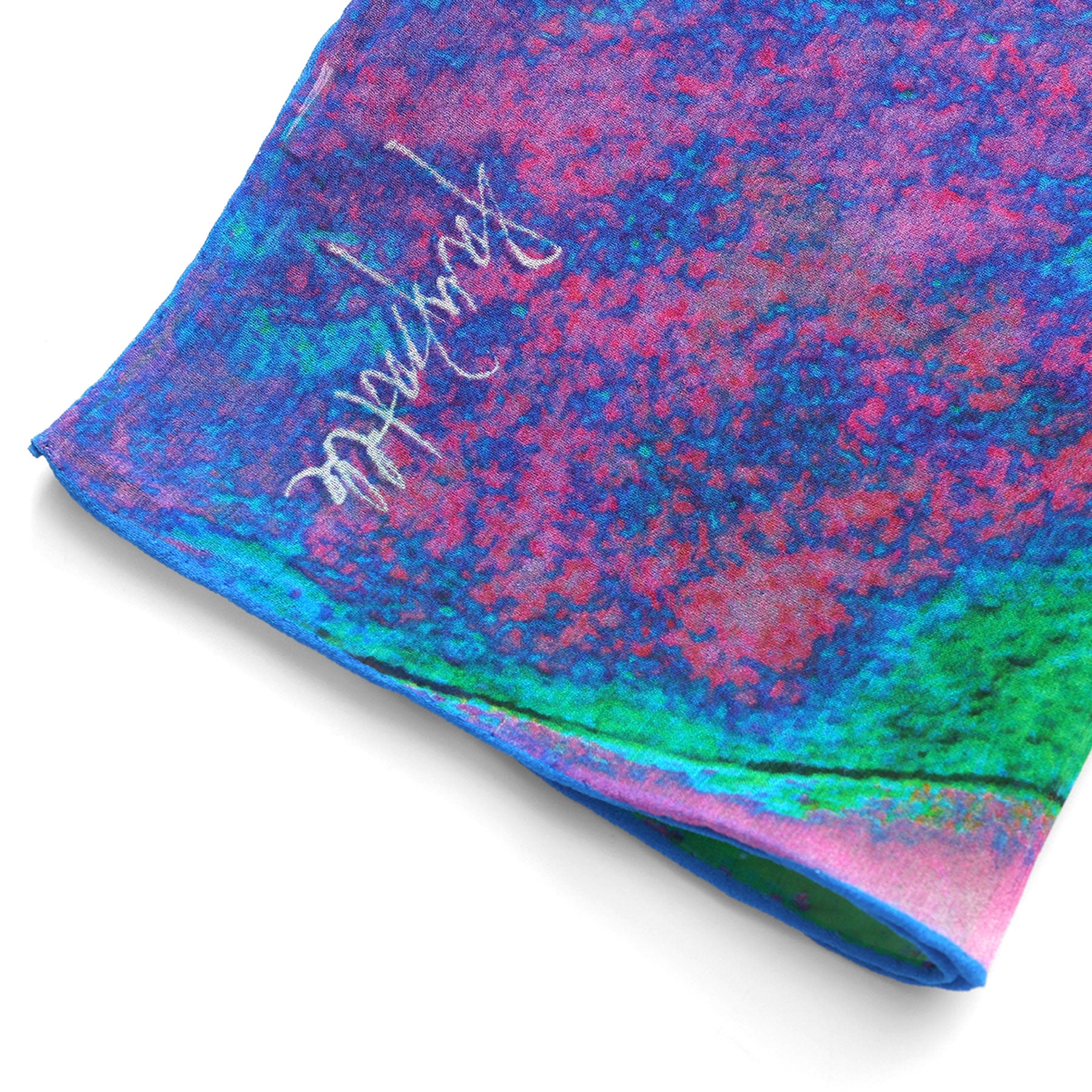 A close-up of the Multicolor Silk Scarf Océano Fucsia, featuring vibrant blue, pink, green, and purple patterns with white