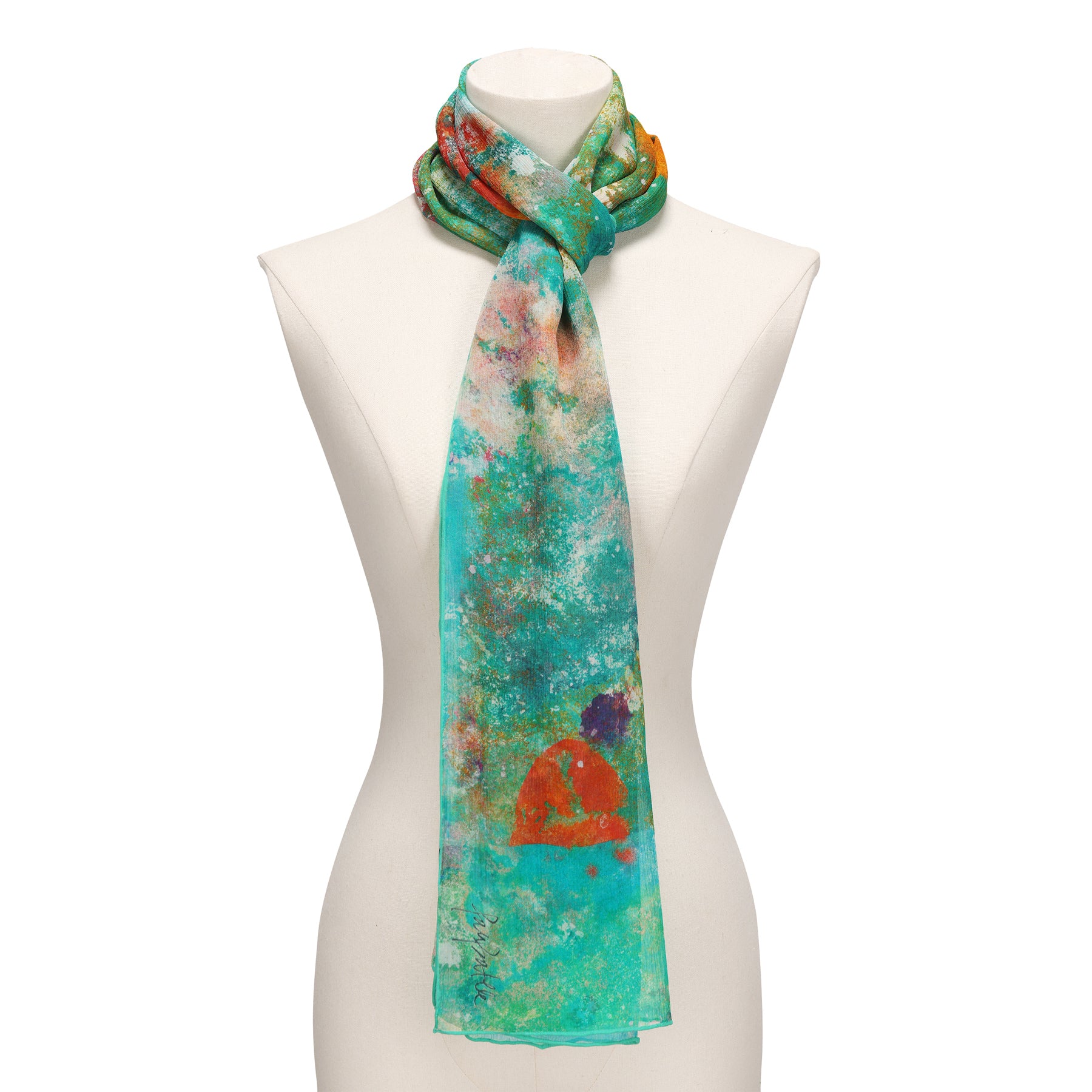 A mannequin showcases the Natural Silk Scarf Mundos Ocultos, featuring turquoise, green, orange, and red abstract patterns—elegantly knotted around the neck as a stunning piece of wearable art.