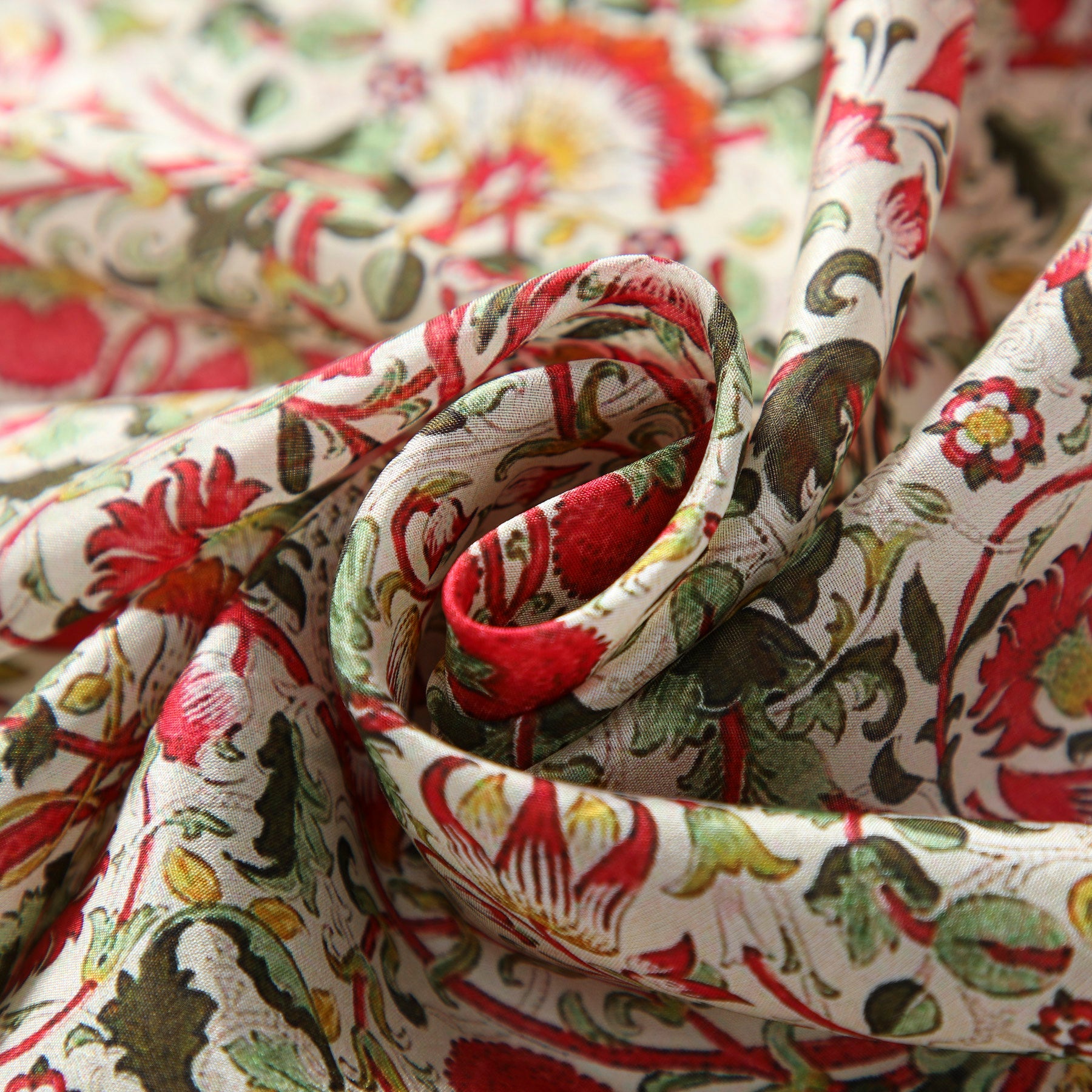 Close-up of the William Morris inspired Silk Scarf - Margaret in Habotai silk, featuring an intricate floral pattern in red, green, and yellow, softly folded to highlight its detailed design and luxurious texture.