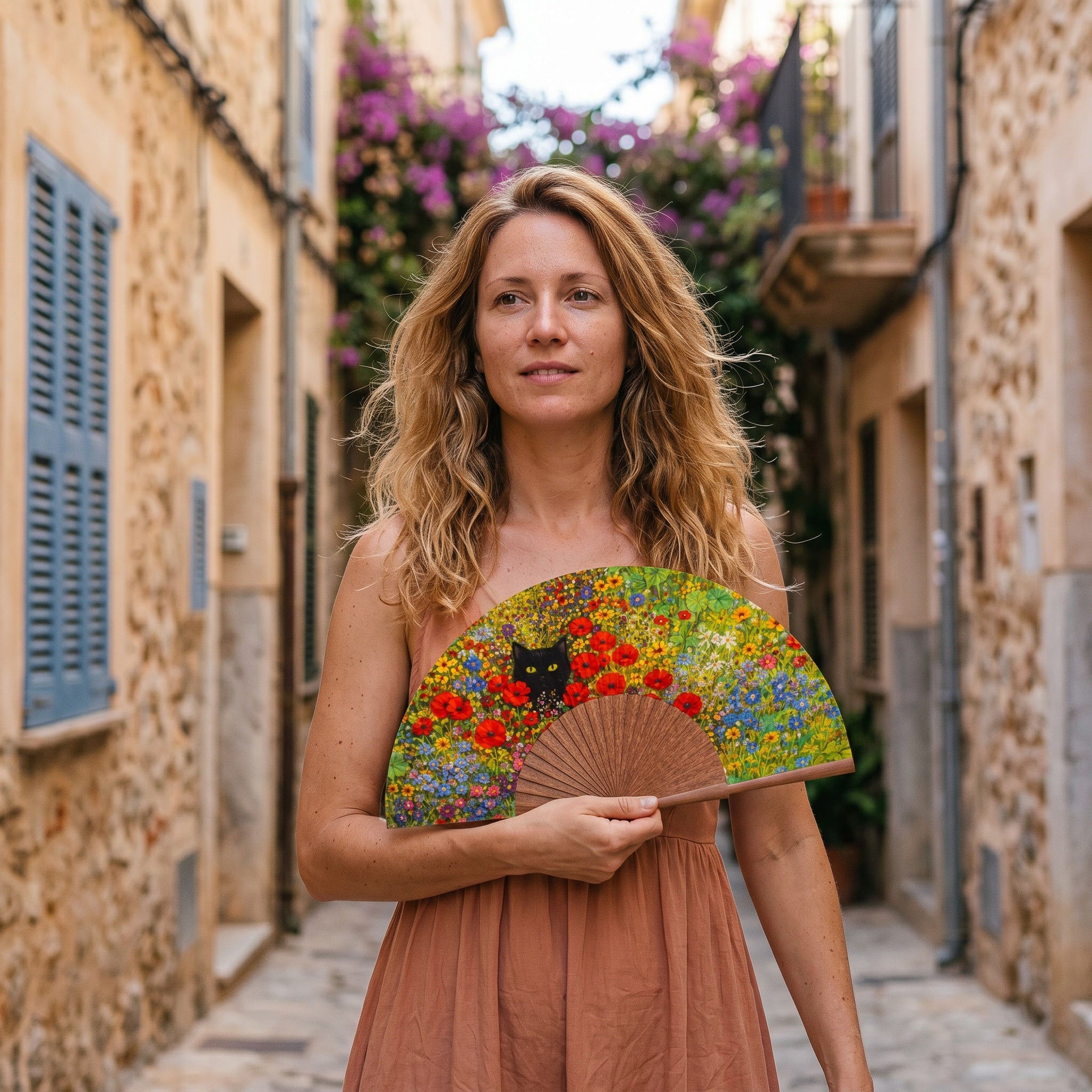 A woman in a summer outfit holding the open Gustav Klimt Print Hand Fan Cat and Flowers with its Gustav Klimt cat and flowers print.