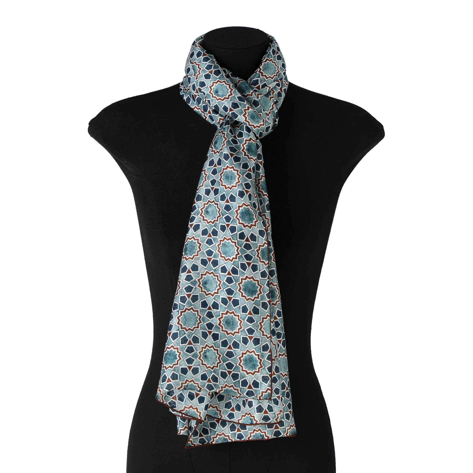 The Islamic Art Design Silk Scarf Rihla V1, in light blue Habotai silk with dark blue and white geometric motifs inspired by Islamic art, is elegantly draped around the neck of a black dress form mannequin.