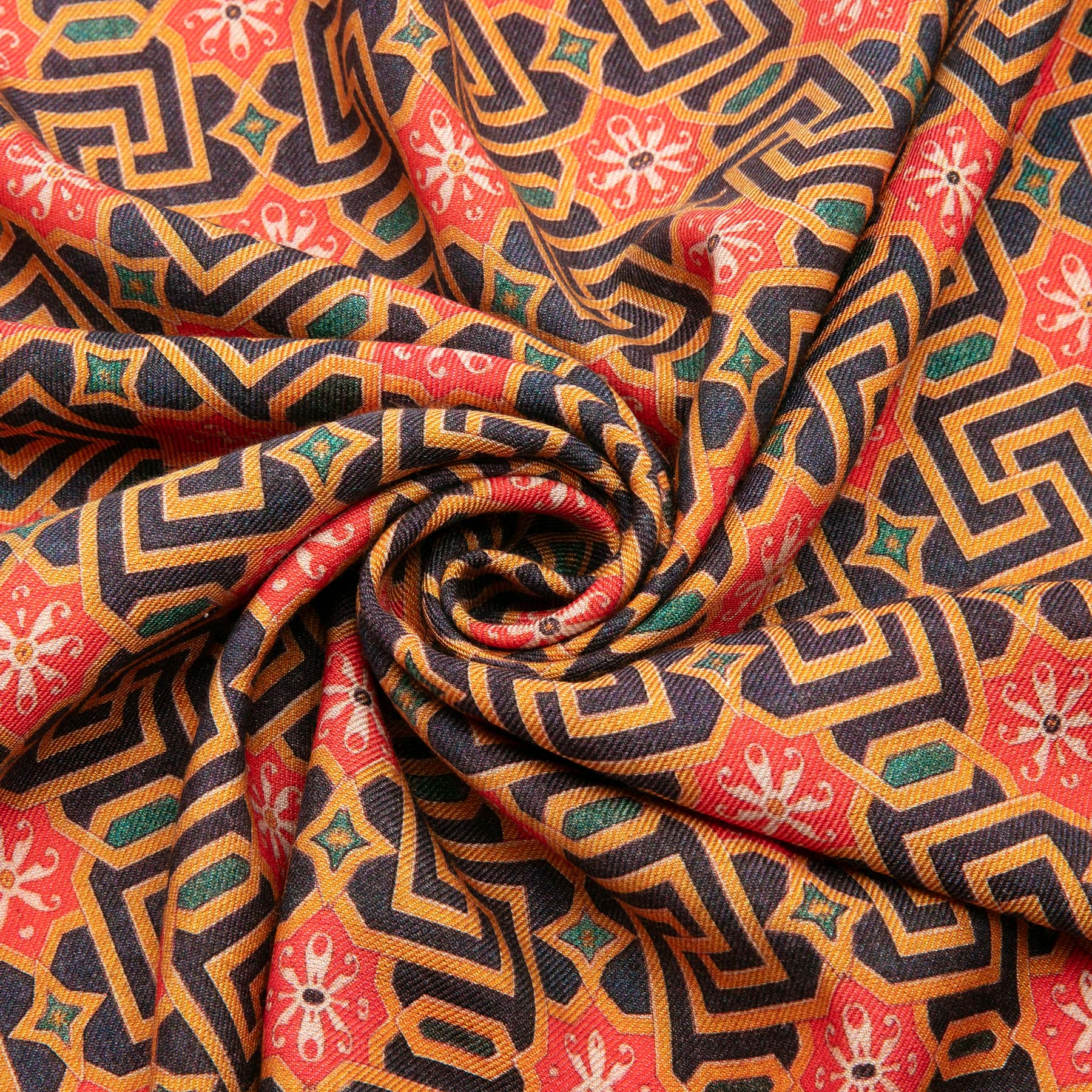The Silk and Wool Scarf Lyabi features a geometric and floral pattern in vibrant orange, black, red, and green tones inspired by Islamic art, gathered in a swirl at the center for a luxurious sense of movement.
