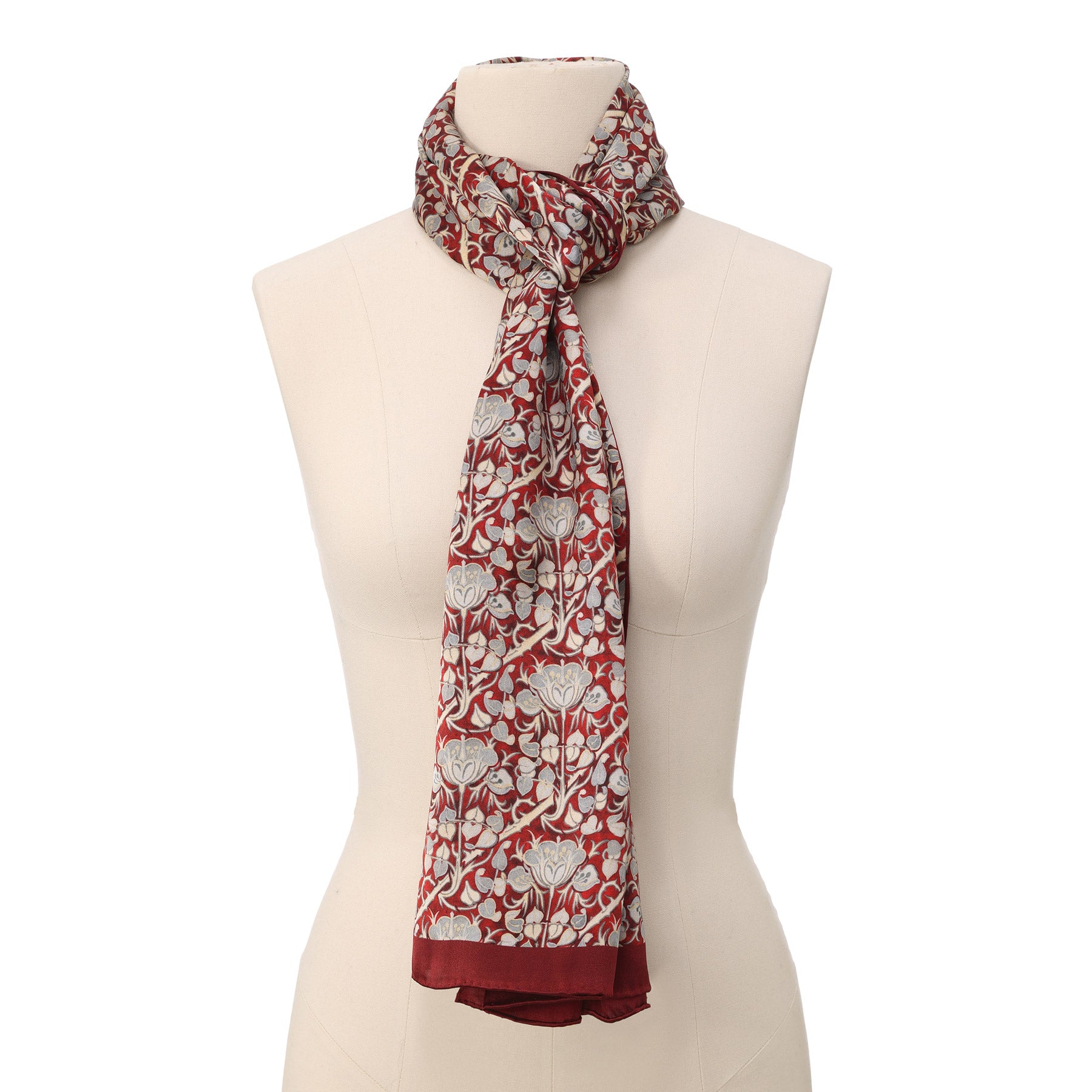 A close-up of the Burgundy and Gray Silk Scarf with Roses Print Noisette, featuring an intricate floral pattern in cream, gray, and gold on a deep red background, elegantly draped in soft folds.