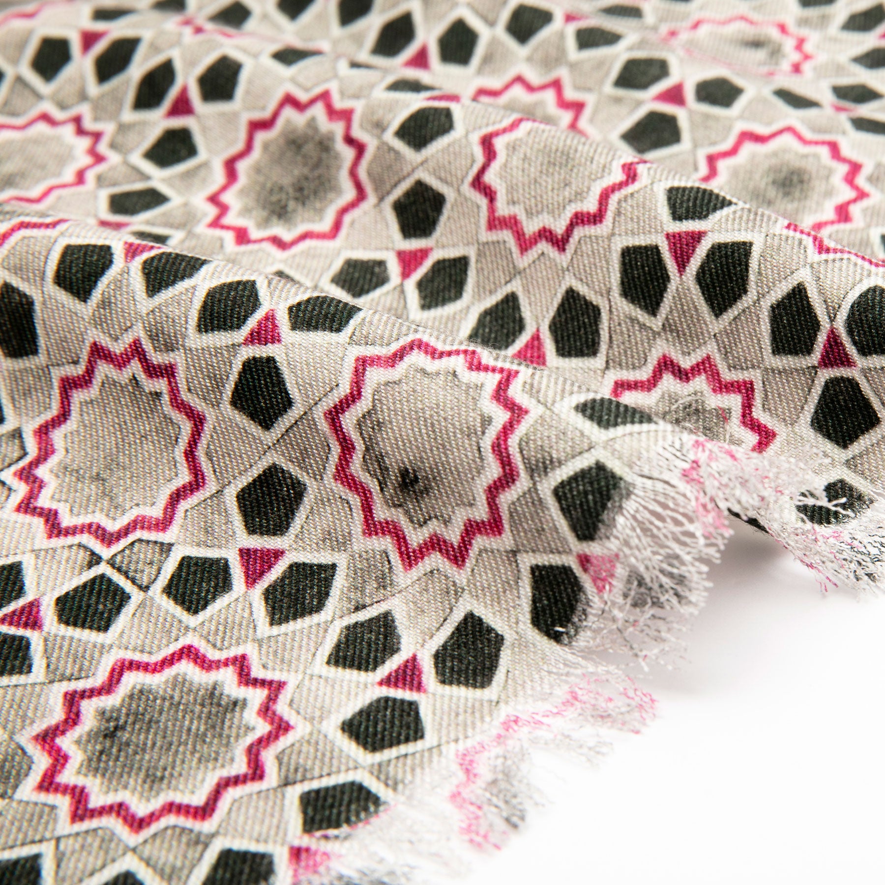 A close-up of the Gray & Red Silk Wool Scarf Rihla V2, featuring a geometric star pattern inspired by Islamic art in black, beige, and red, with frayed edges and a slightly gathered look that highlights its intricate repeating design.