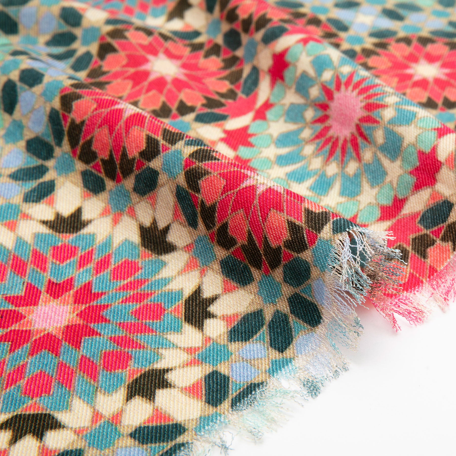 A close-up of the Large Silk and Wool Multicolor Scarf Baraka V1, featuring star and floral motifs in red, teal, black, and cream on textured fabric with fringed edges that showcase exquisite cultural artistry.