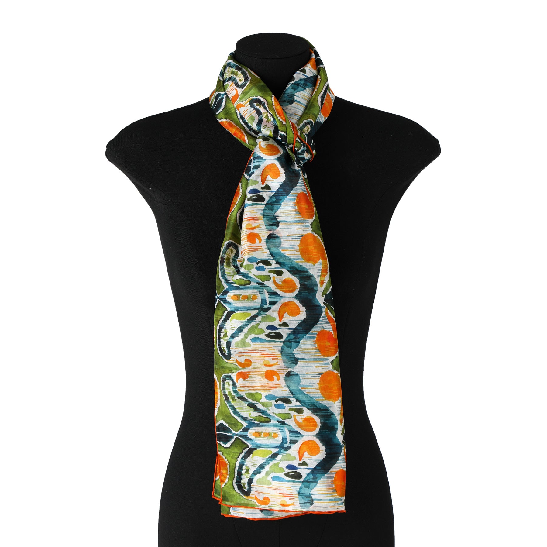 A black mannequin displays the Hamzah Green and Orange Silk Scarf with Ikat Print, featuring vibrant abstract patterns in blue, orange, and green on habotai silk. The scarf is elegantly wrapped around the neck and softly drapes down the front.