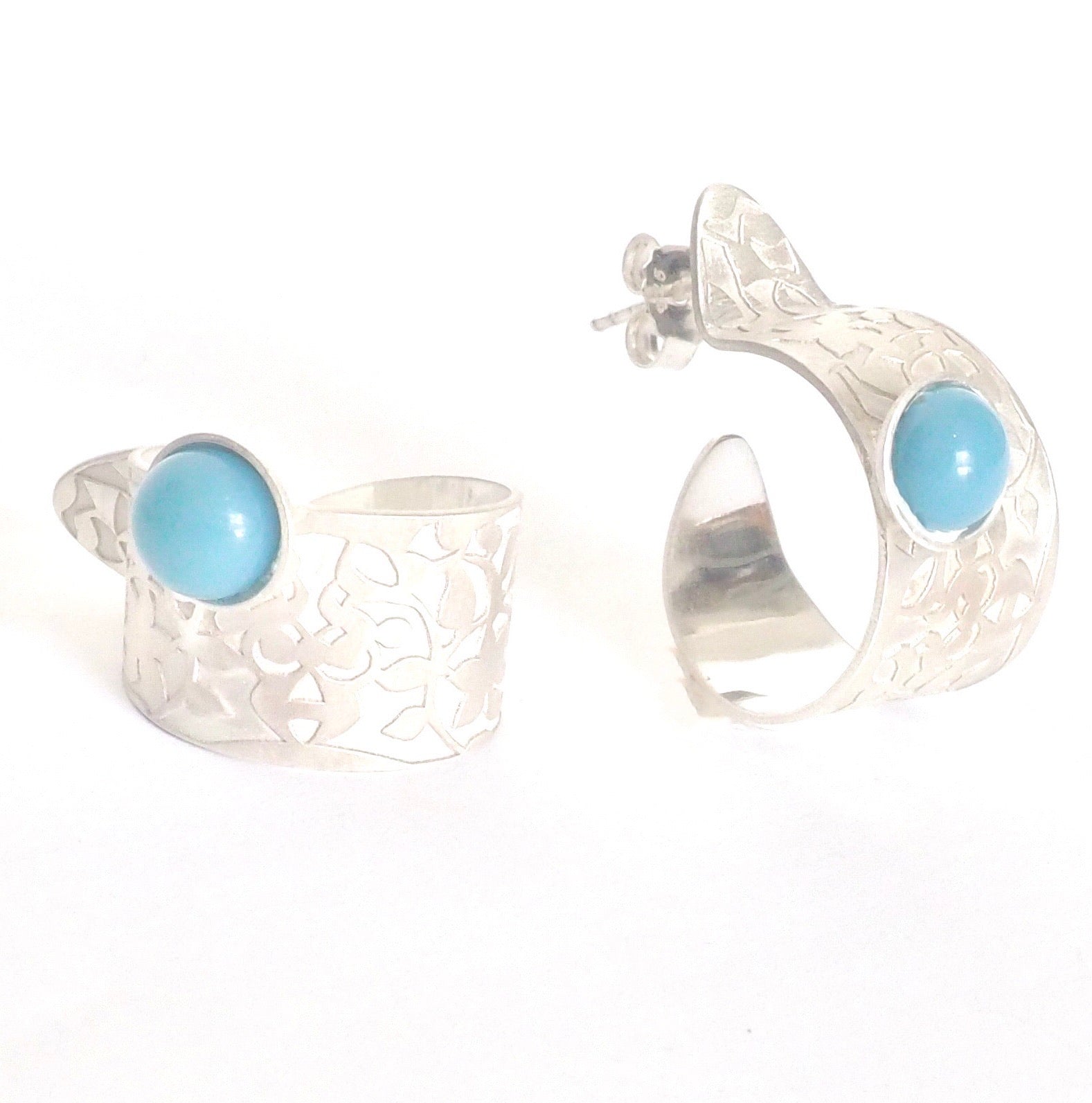 The Blue Nasrid Palaces Detail Hoops by Platónica are silver cuff earrings from the Alhambra collection, showcasing intricate floral patterns and round turquoise stones on a white background. Crafted in 925 silver, they add elegance to any outfit.