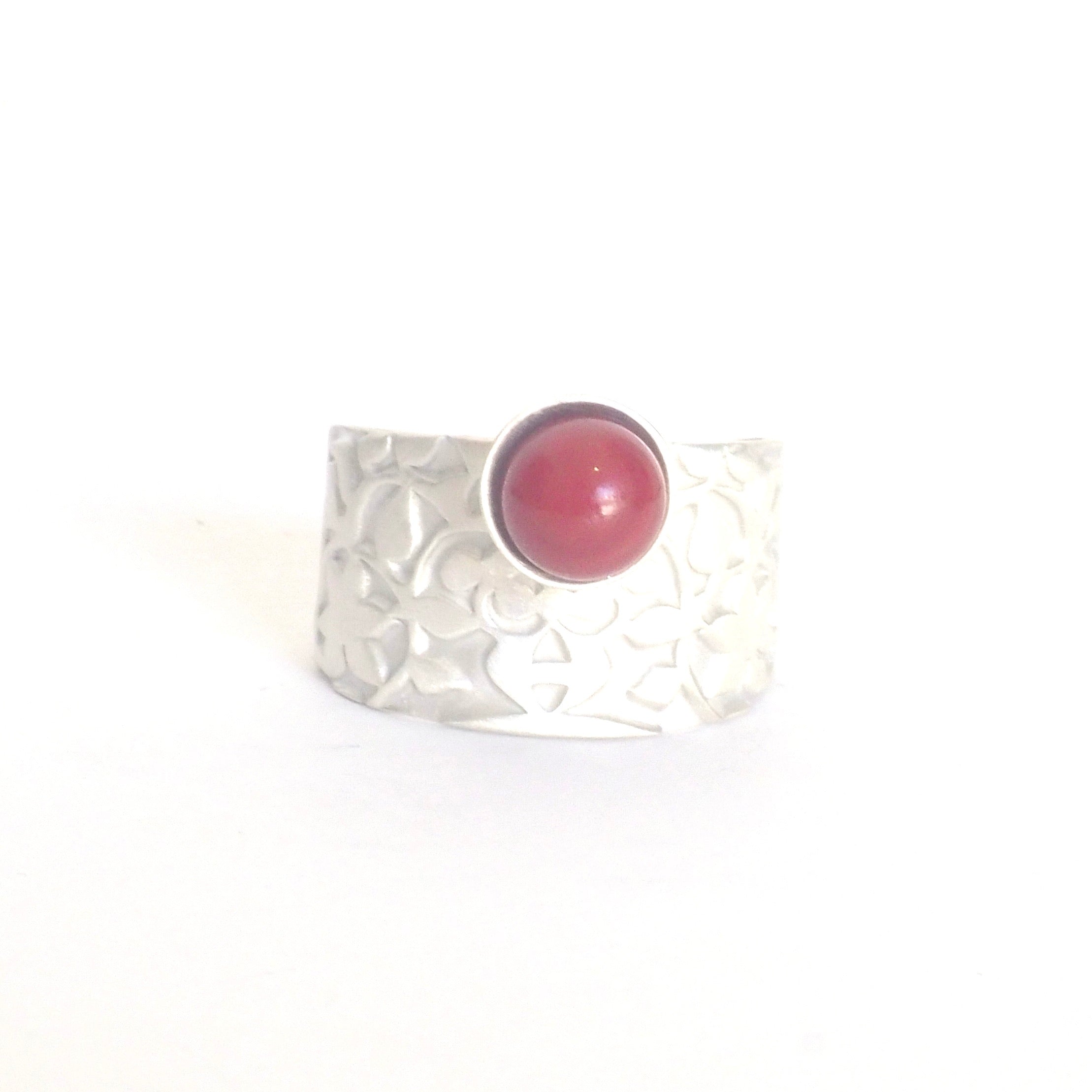 The Red Nasrid Palaces Detail Ring by Platónica features a 925 silver band with a textured floral design and a round red stone, evoking the Alhambra collection, set against a plain white background.