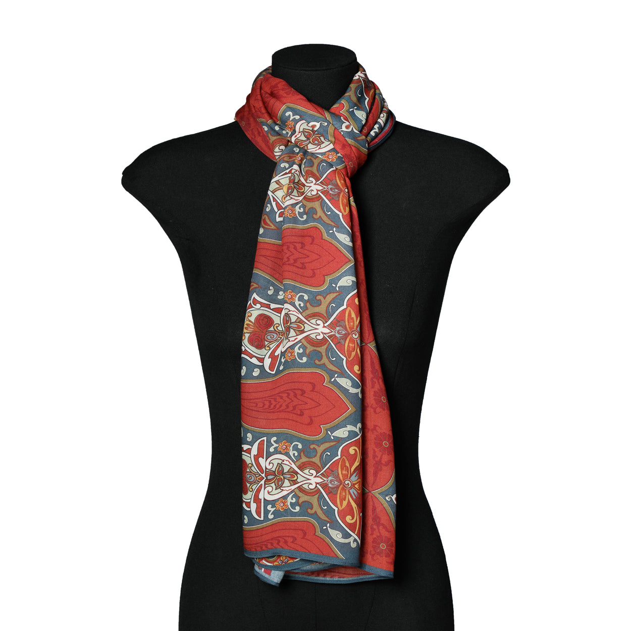A black mannequin showcases the Isfahan-Inspired Red & Blue Scarf – 100% Modal, featuring intricate gold patterns based on traditional art, draped and loosely tied at the neck.