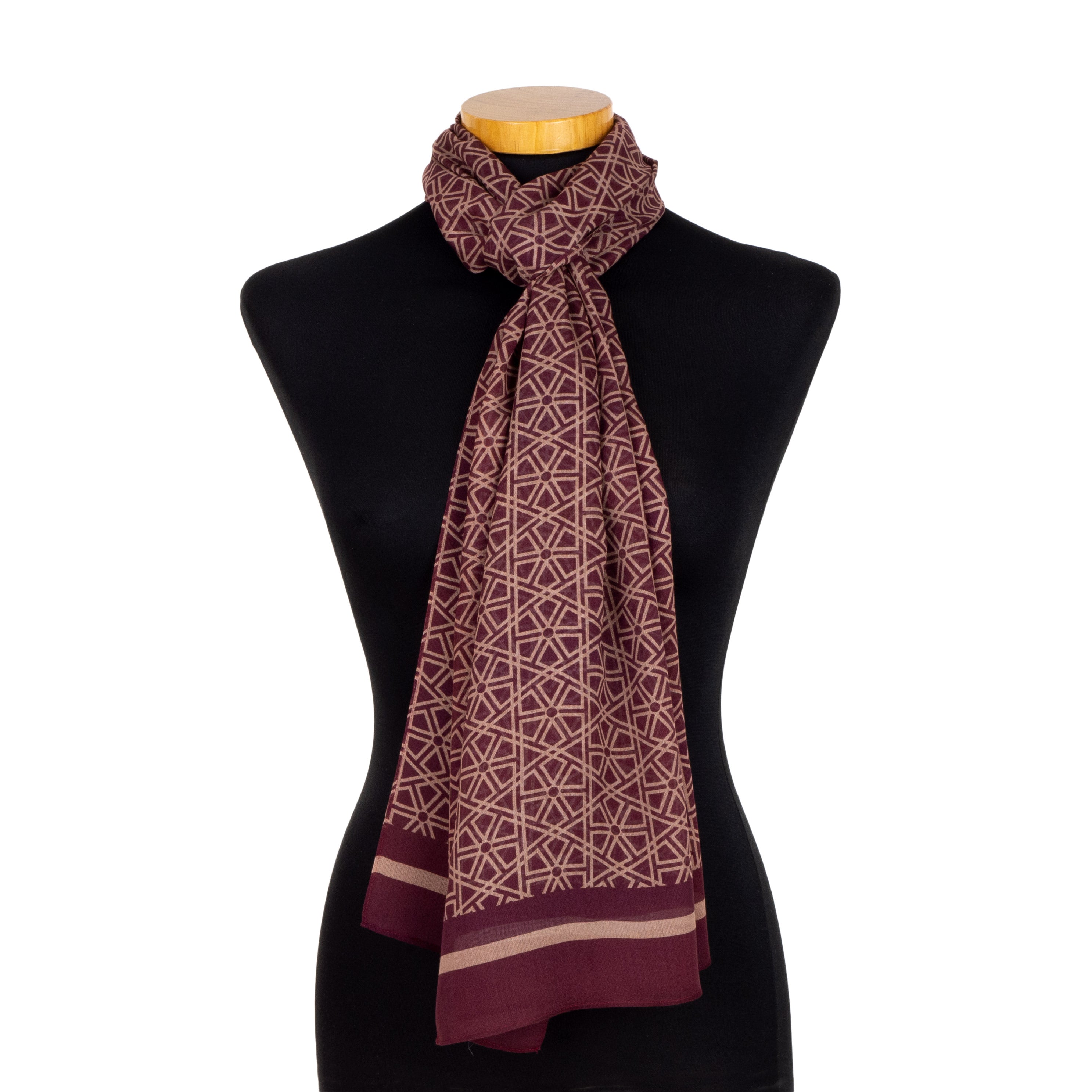 The Red and Beige Scarf Taif v2, designed in Spain with Alhambra-inspired motifs and a geometric border, is displayed on a black mannequin bust with a light wooden neck cap.
