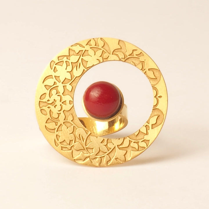 The Platónica Alhambra Palace inspired Gold Ring with Red Stone features an exquisite gold ornament with intricate floral patterns and a central red oval gem, exuding delicate elegance.