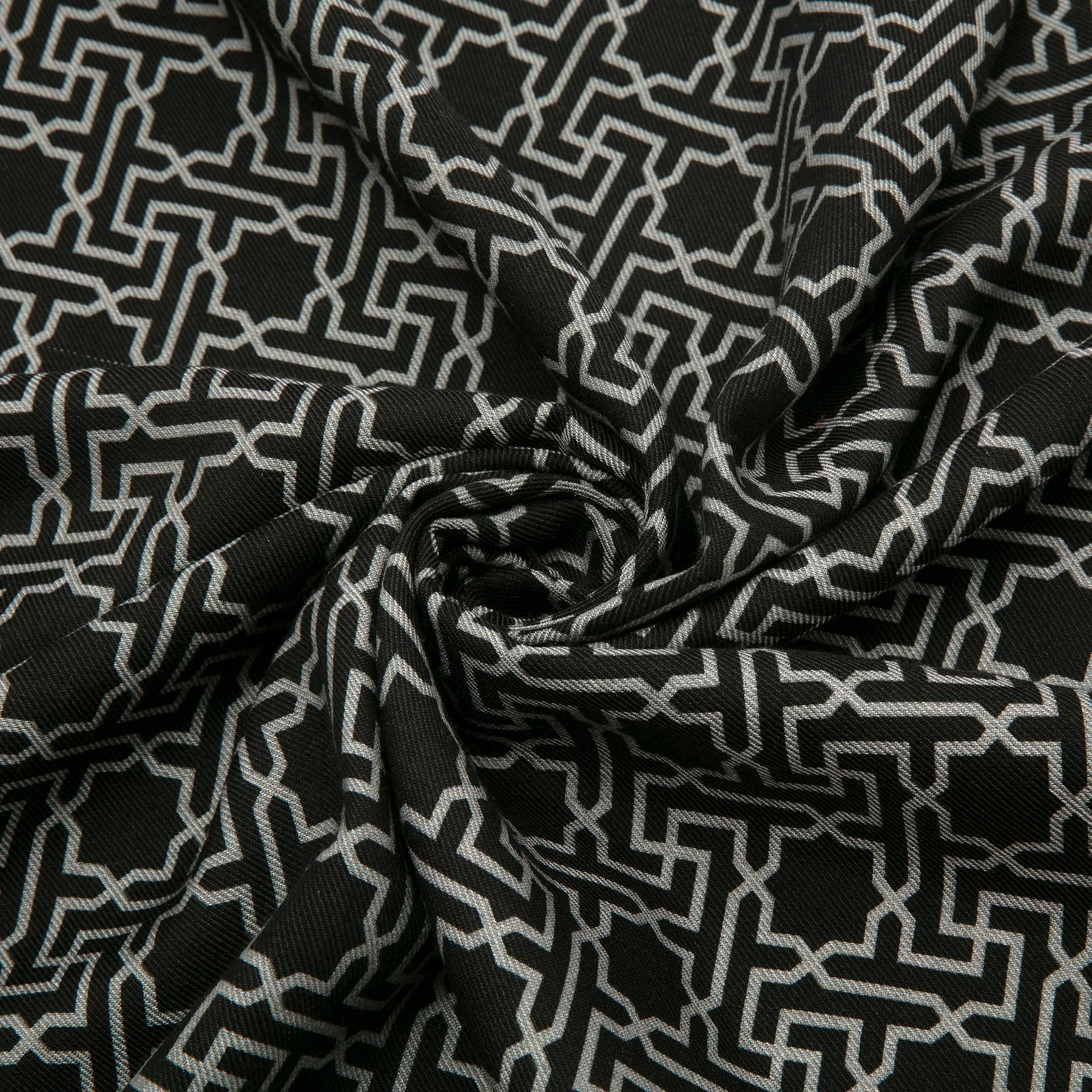 The Silk Wool Black and Gray Scarf Rawdah V1 features a repeating Islamic geometry-inspired print in white, with a gathered and twisted spiral center that accentuates its folds and luxurious silk-wool texture.