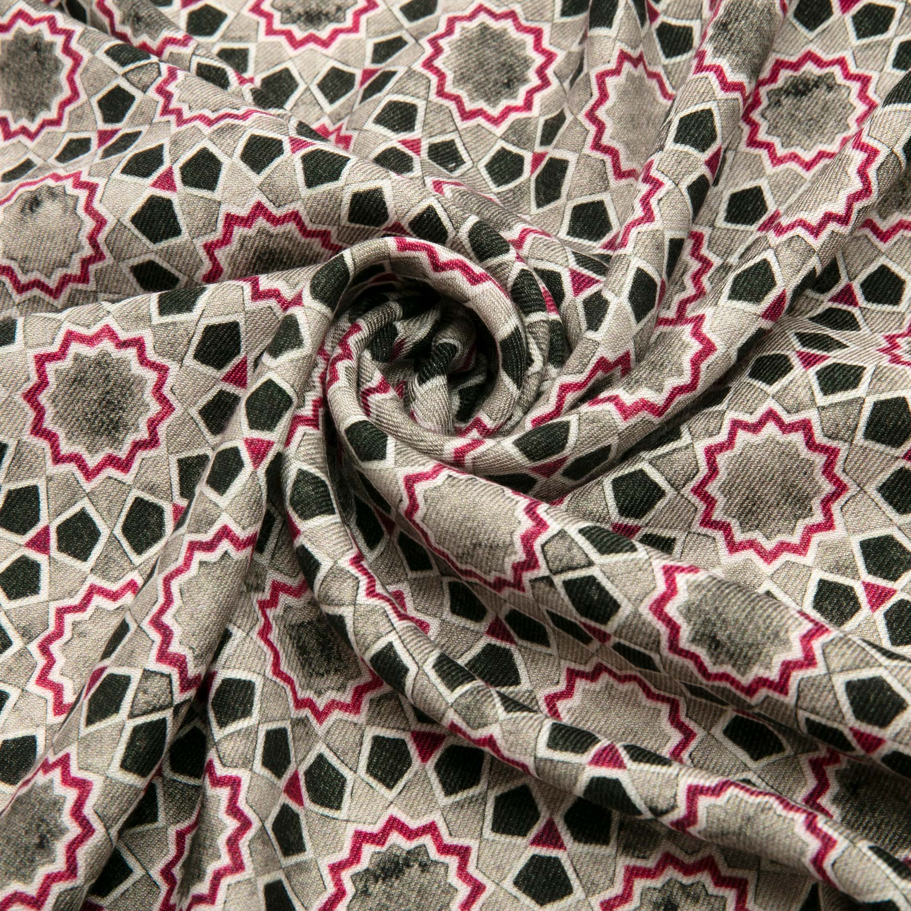 A close-up of the Gray & Red Silk Wool Scarf Rihla V2, showcasing geometric star and diamond motifs inspired by Islamic art in black, gray, and red tones, beautifully arranged in a central spiral fold.