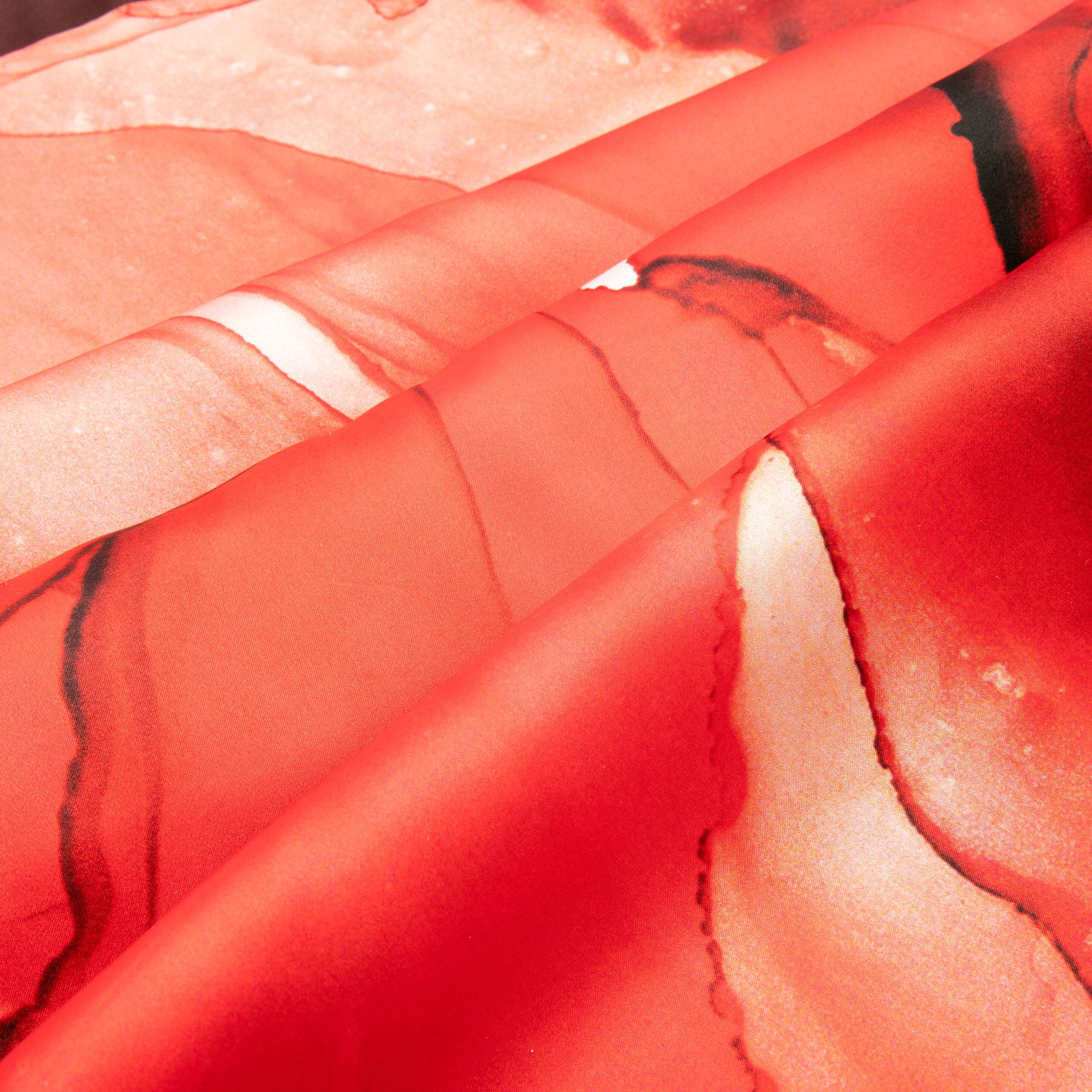 Close-up of the Red Silk Scarf Square Fluid Art, featuring orange marbled patterns and swirling abstract shades on satin silk. The scarf’s folds highlight its intricate color transitions and fluid, elegant texture.