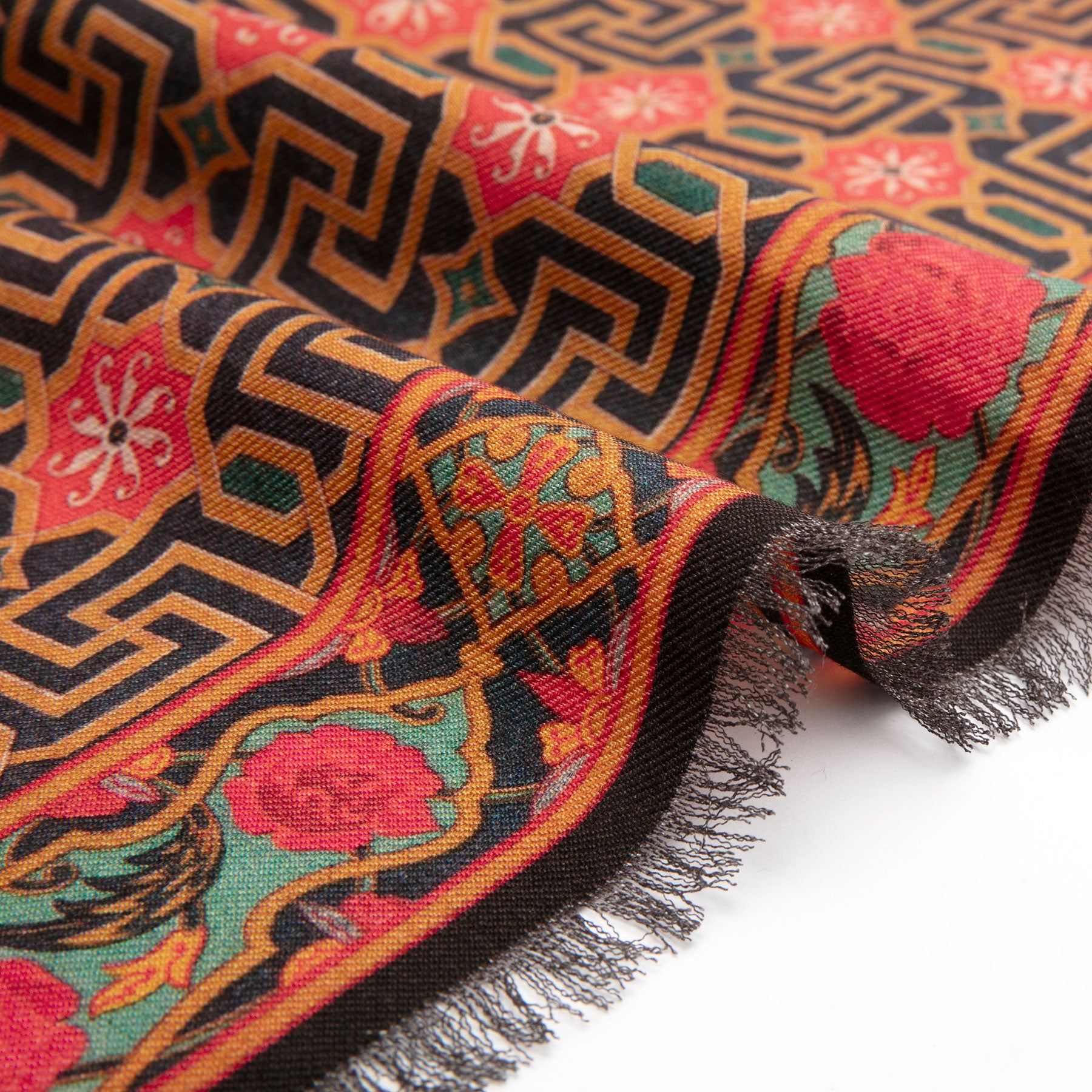 A close-up of the Silk and Wool Scarf Lyabi, featuring intricate geometric and floral patterns in red, black, gold, and green inspired by Islamic art. Fringed edges and fine weave enhance the luxury of this elegant scarf.