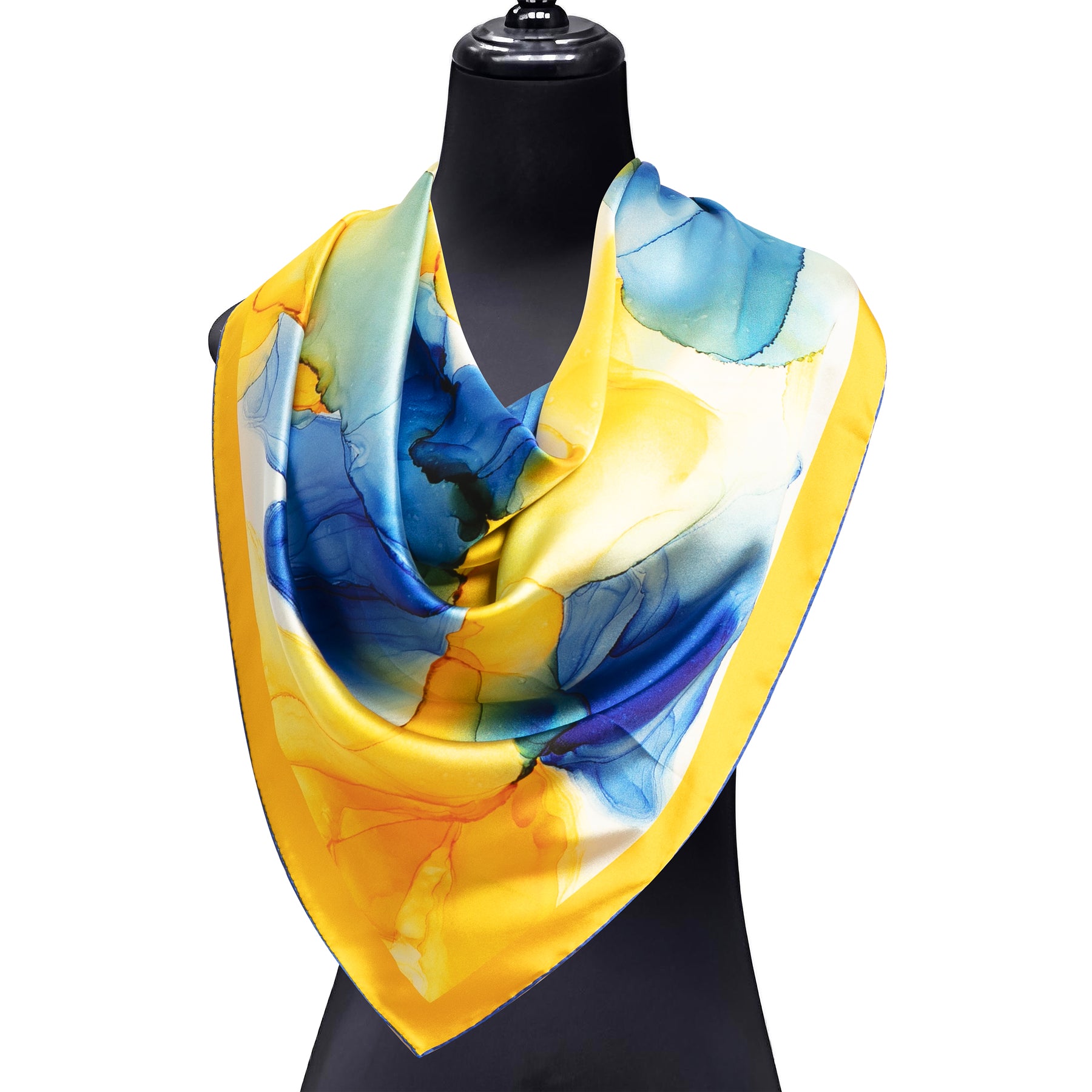 A mannequin showcases the Hamzah Yellow and Blue Silk Scarf Square with a fluid art print in watercolor tones of yellow, blue, and green, featuring a yellow border. Crafted from soft satin silk, it is draped stylishly around the neck.