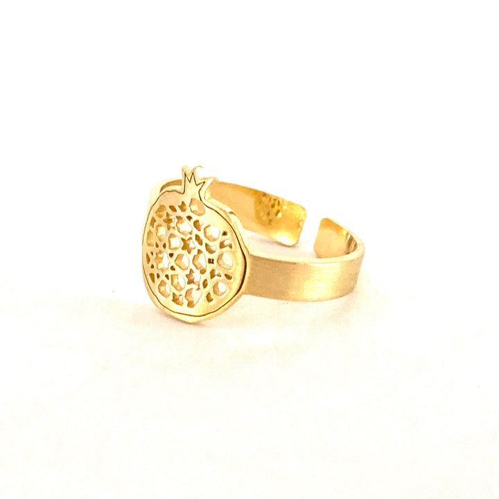 The Gold Plated Thin Ring Granada No.4 by Platónica showcases an intricately detailed, textured pomegranate design on a minimalist band, set against a white background.