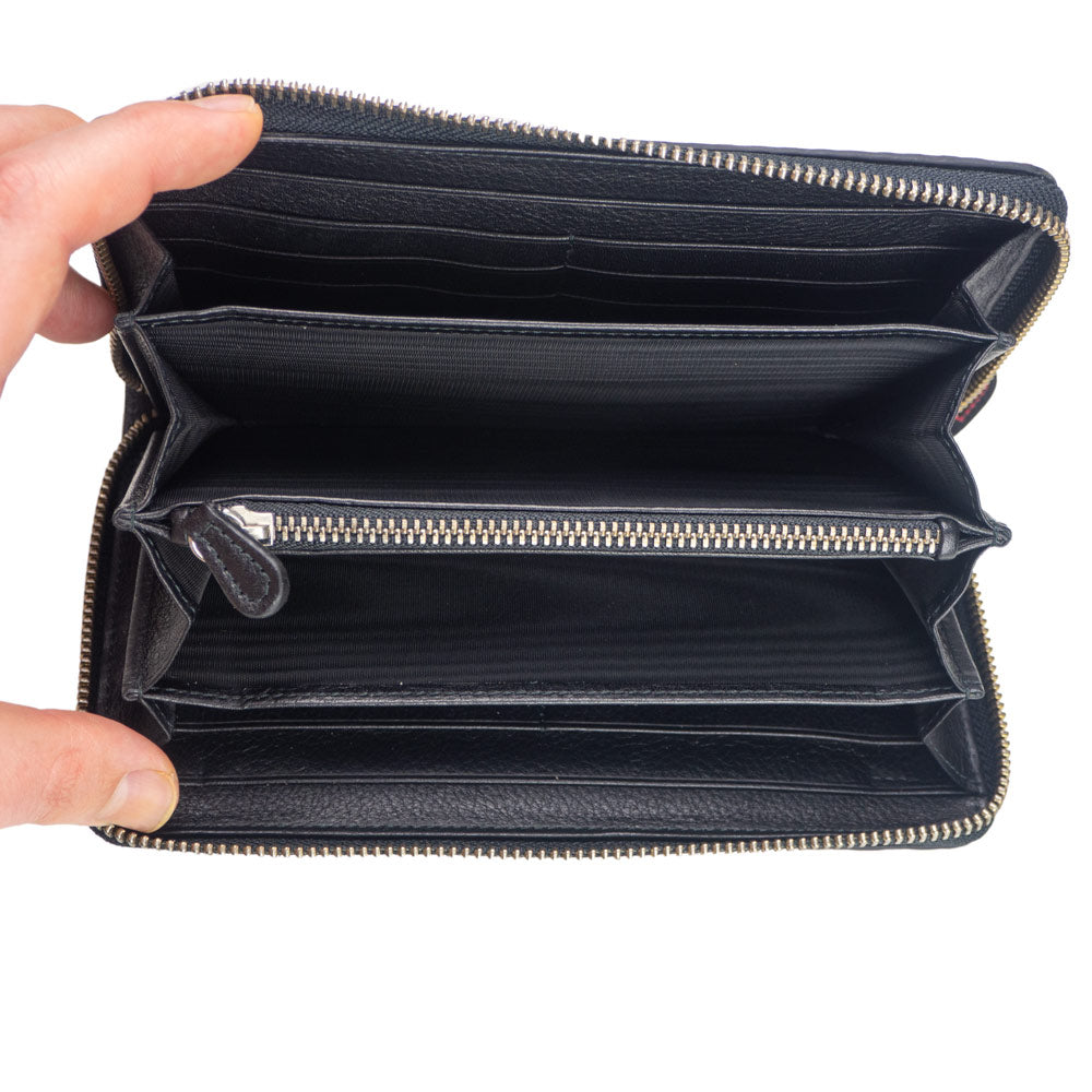 A hand is holding open a Munira Leather Large Leather Wallet with Zipper in Blue, showing its embossed pattern, multiple compartments, and card slots inside.