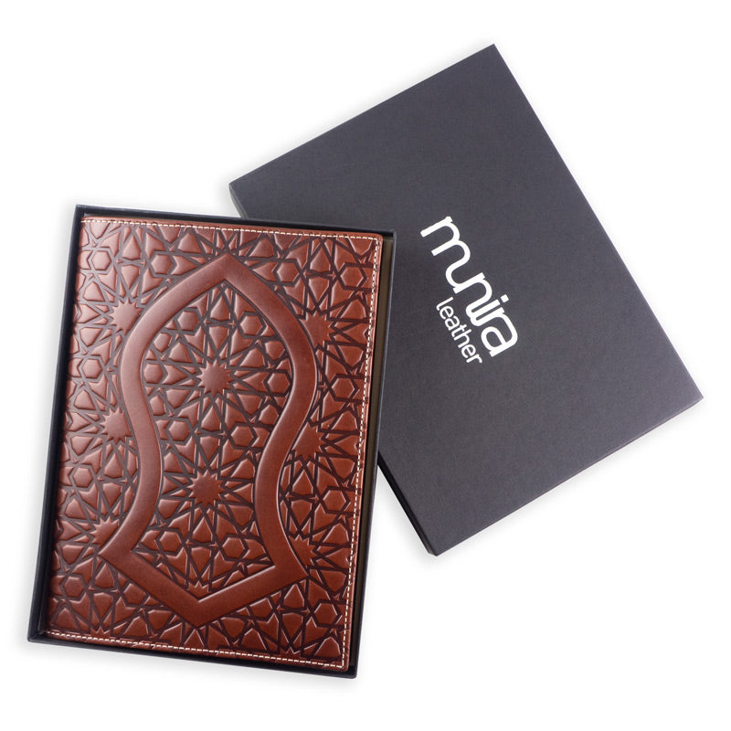 The Na´layn Leather Journal Cover Dark Brown by Munira Leather features an embossed geometric and arabesque pattern. It is partially placed inside a black Munira Leather box on a white background.