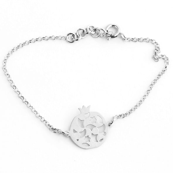The Sterling Silver Bracelet Granada No.2 by Platónica showcases a delicate chain with a circular pendant featuring cut-out pomegranates and stars, crafted by Spanish artisans. It includes a small round spring ring clasp, all set on a solid white background.