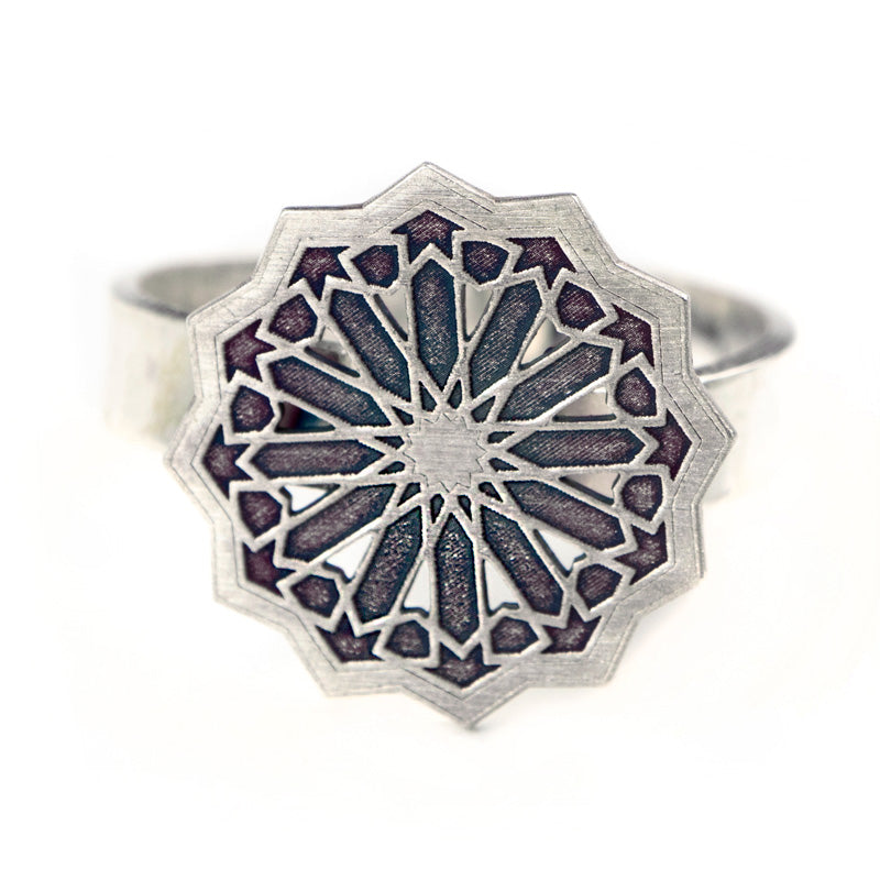 The Silver Ring Estrella by Platónica is a handmade sterling silver piece from Granada, featuring a detailed geometric star pattern resembling intricate stained glass, with a central star surrounded by symmetrical shapes for an artistic and unique look.
