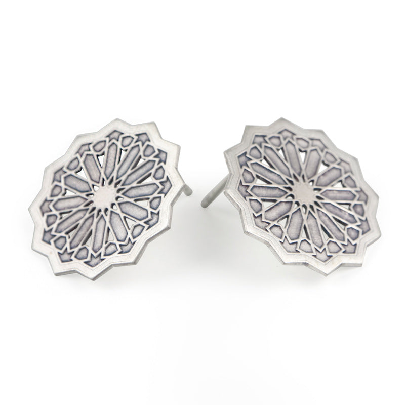 Close-up of Platónicas Sterling Silver Studs Earrings Estrella XXL, featuring intricate geometric star patterns and symmetrical lines. Part of the Andalusí collection, these handmade earrings from Granada boast a polished metallic finish for a detailed, decorative look.