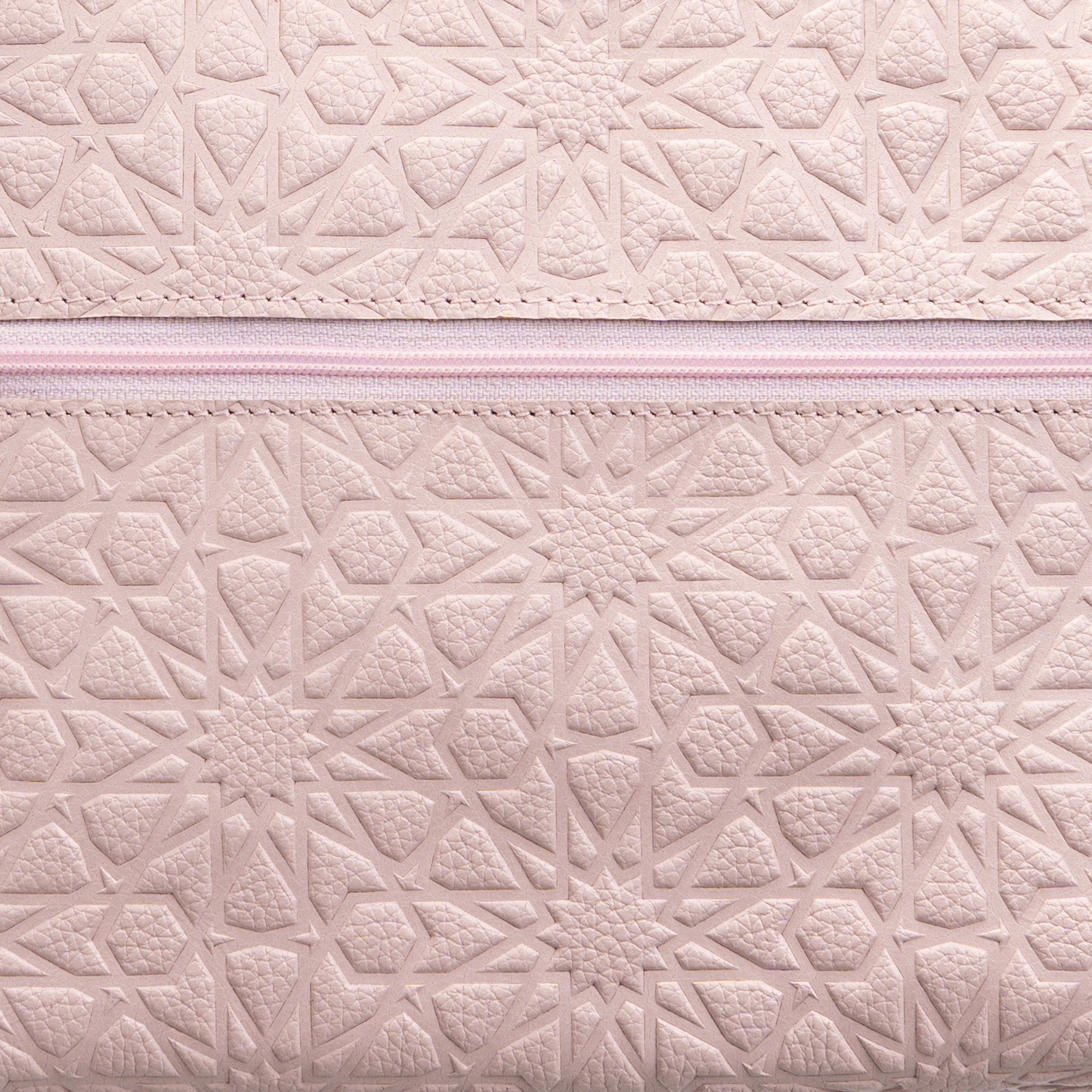 Close-up of a Pale Pink Embossed Crossbody Bag with an Islamic design pattern and a pink zipper running horizontally across the textured surface.