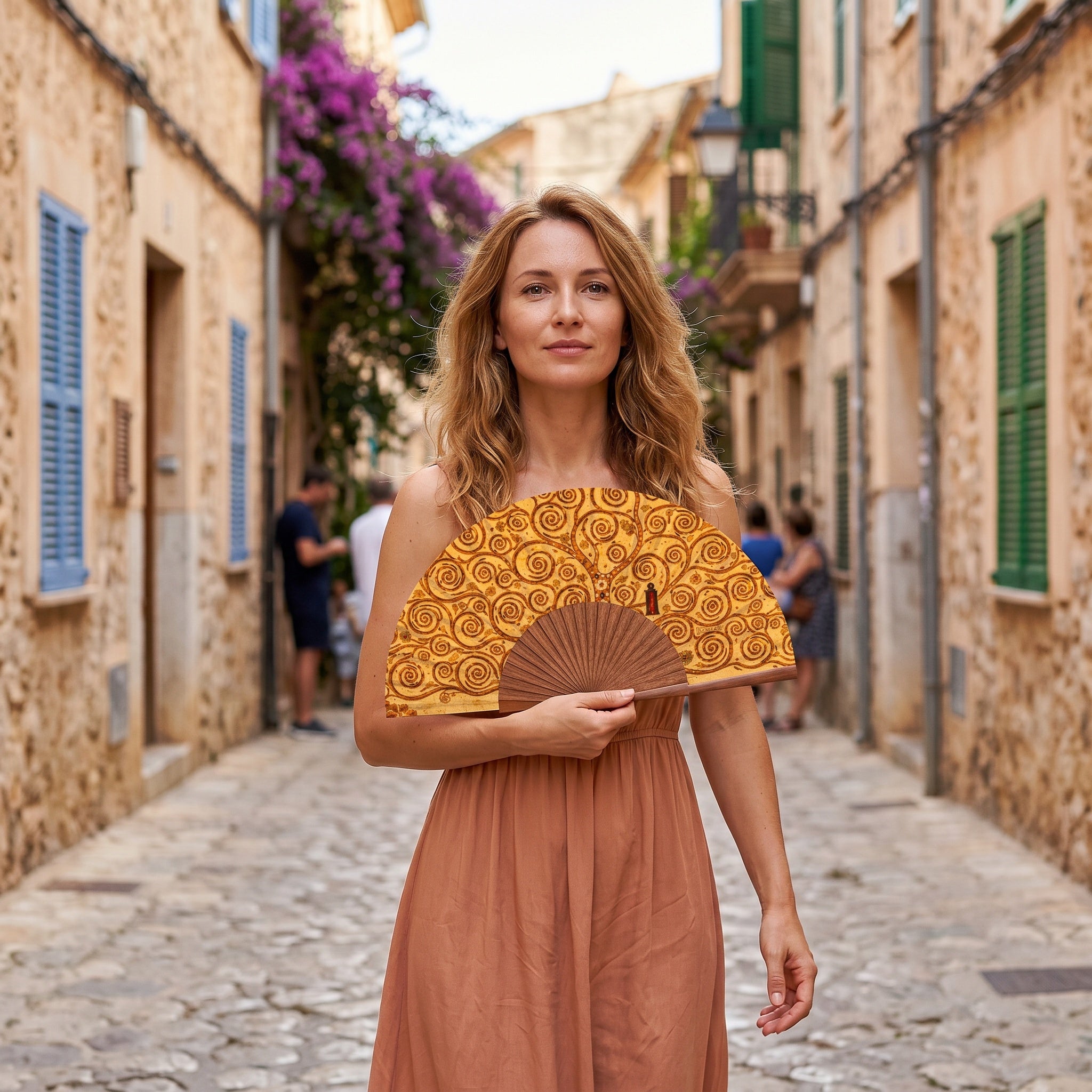 A woman in a summer outfit holding the open Gustav Klimt Print Hand Fan Tree of Life with its Gustav Klimt Tree of Life golden print.