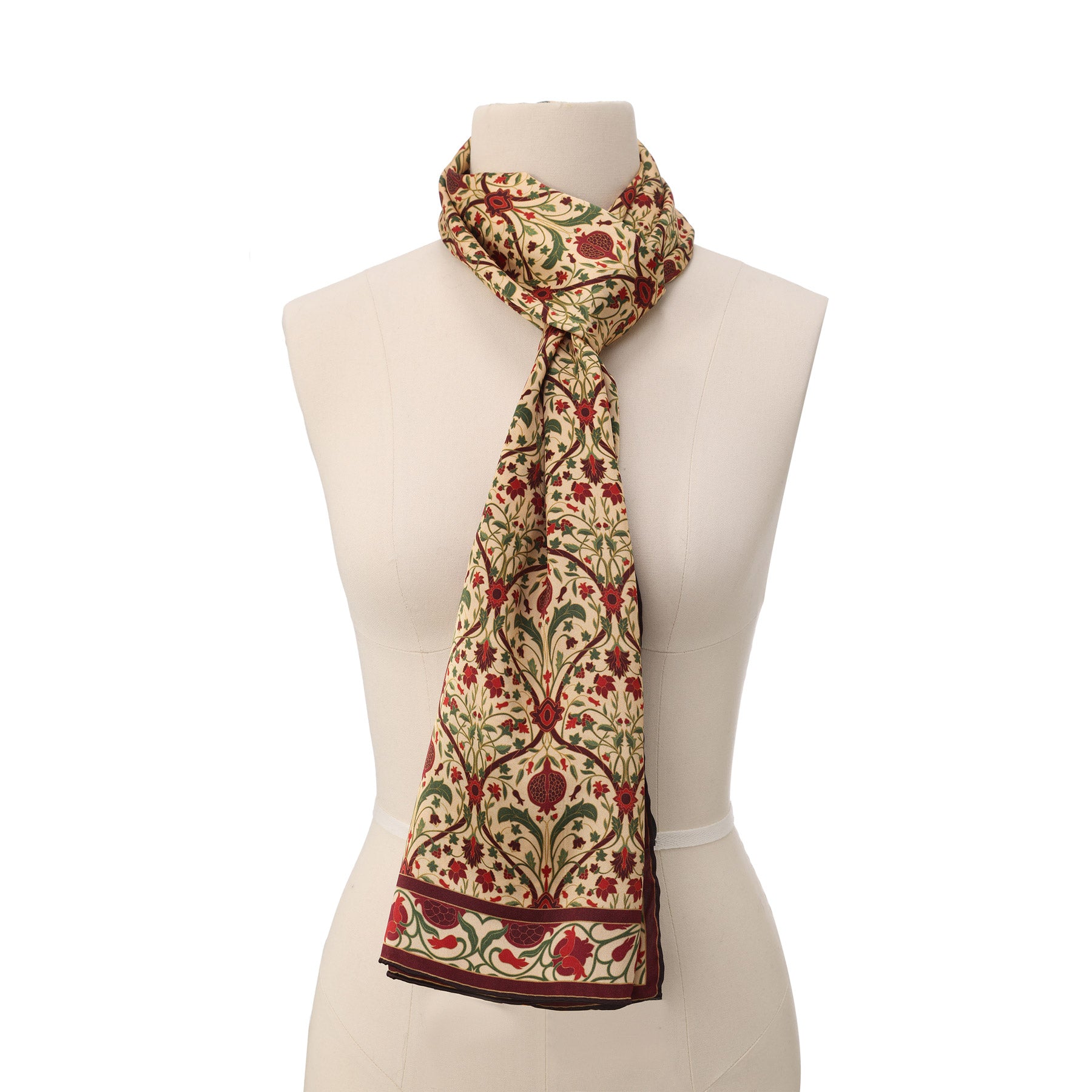 A close-up of the Art Nouveau Silk Scarf Berry shows its intricate floral and pomegranate patterns in red, green, and gold