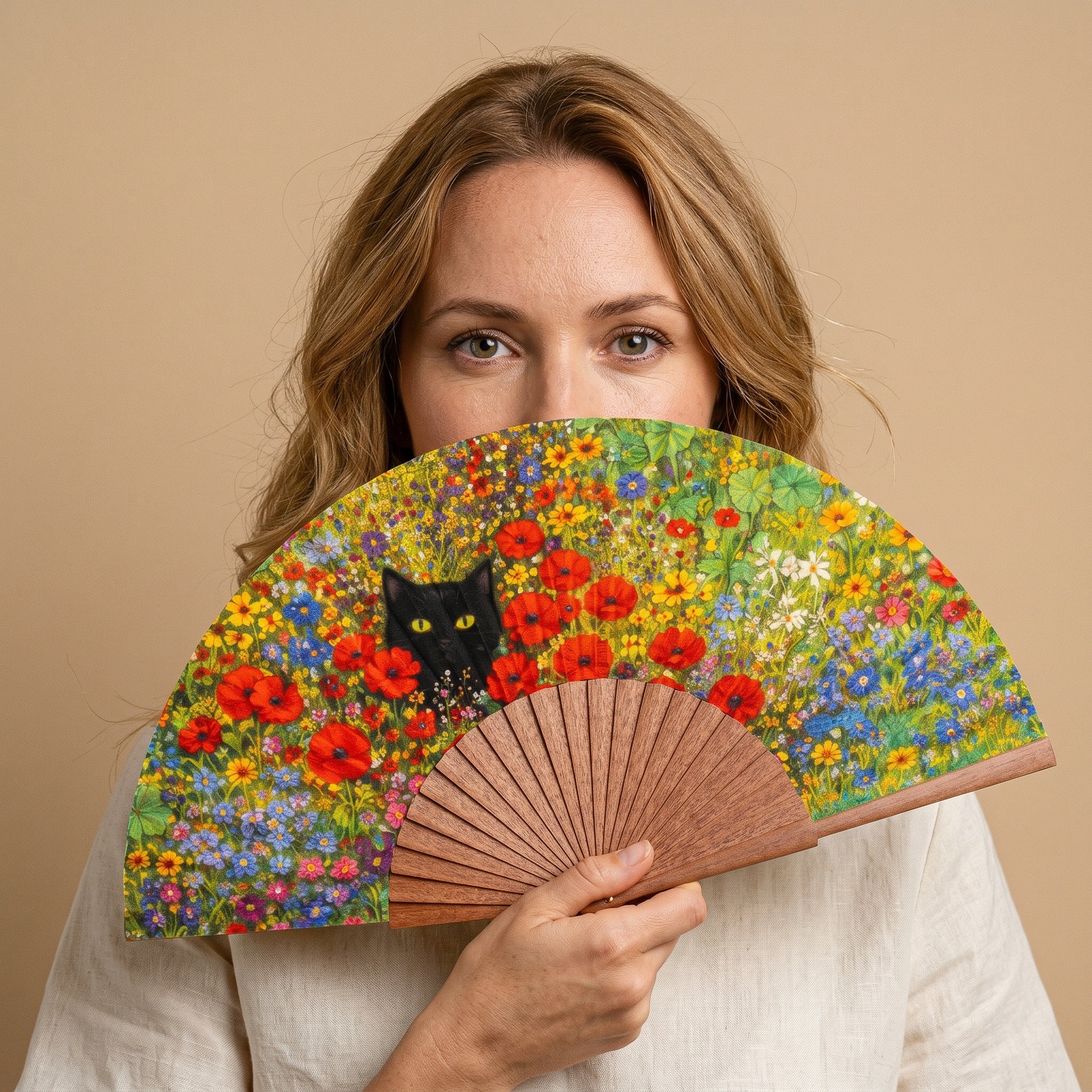 A woman holding the Gustav Klimt Print Hand Fan Cat and Flowers, with its Gustav Klimt cat and flowers print, against a soft neutral background.