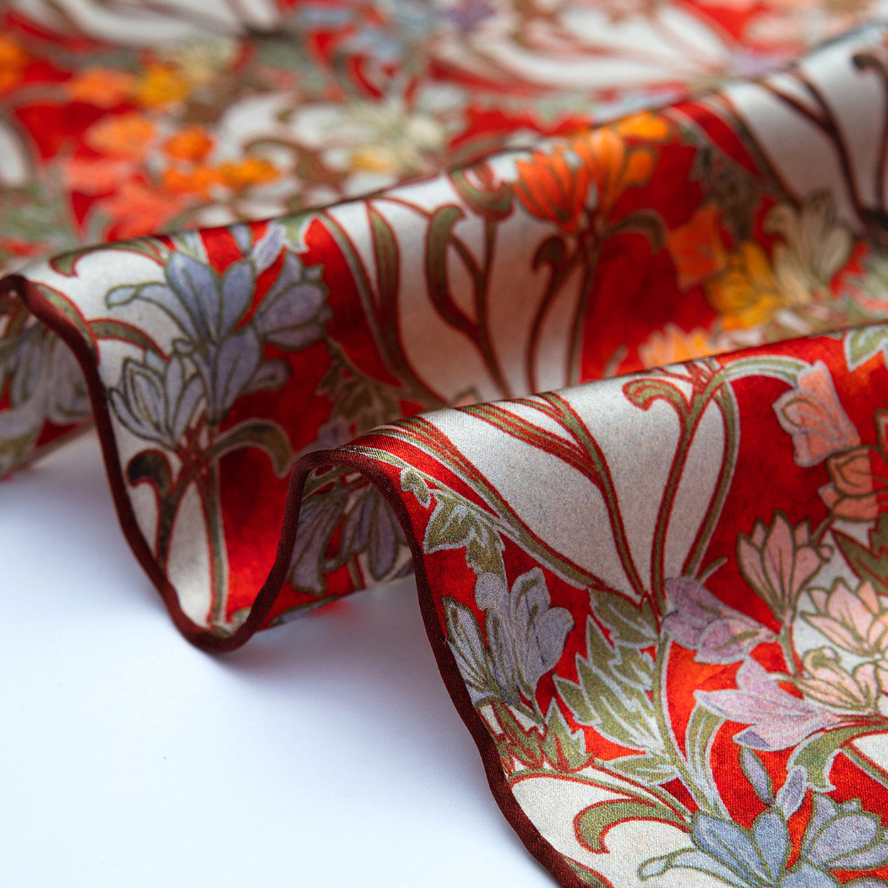 Close-up of the scarf’s hand-rolled edge, revealing art deco-style motifs and a smooth satin finish.