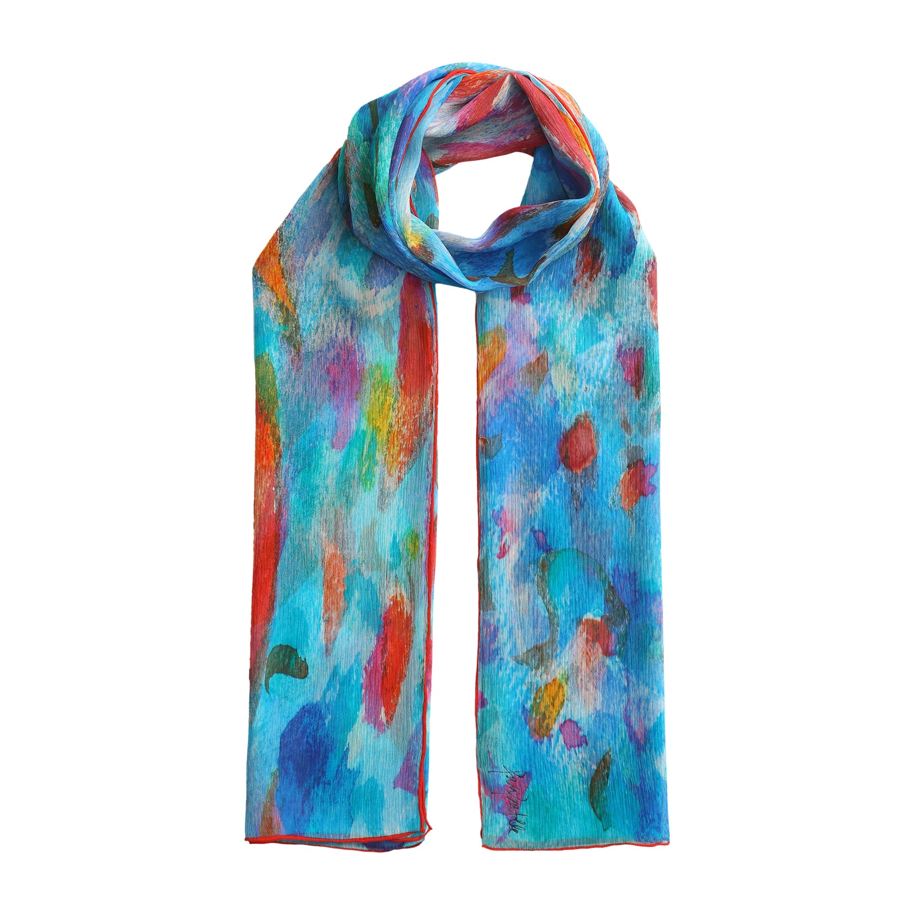 The Multicolor Silk Scarf Mar Rojo, a lightweight muslin silk piece featuring vibrant abstract blue, red, orange, and green patterns, is shown draped in a simple loop against a white background—a wearable work of art.