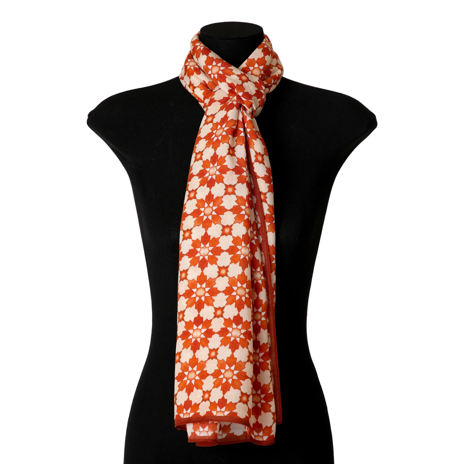 An orange scarf featuring an Islamic pattern print is draped and tied around the neck of a black mannequin torso.