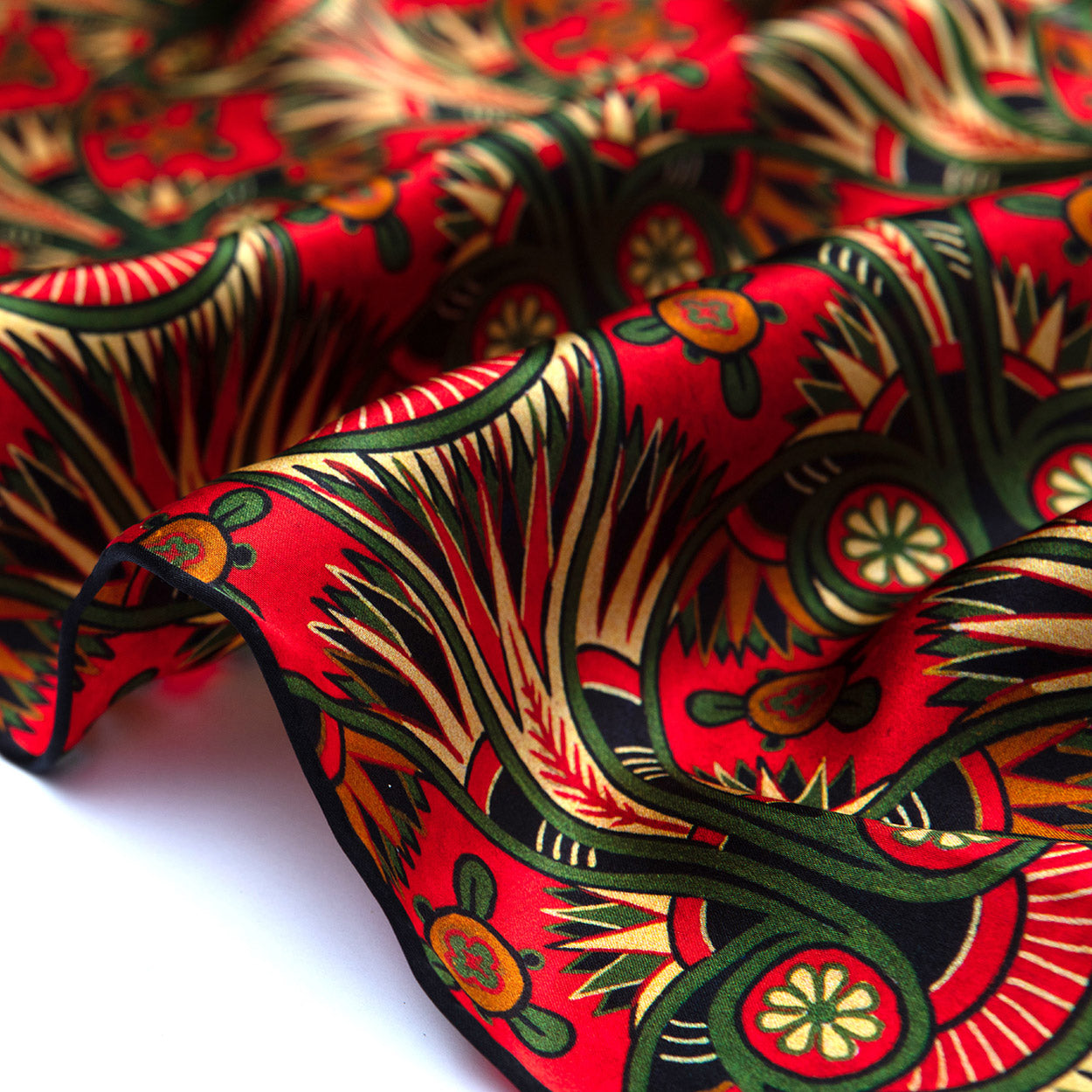 Close-up of the scarf’s dark hem, revealing green vines and gold floral accents on a crimson art nouveau pattern.