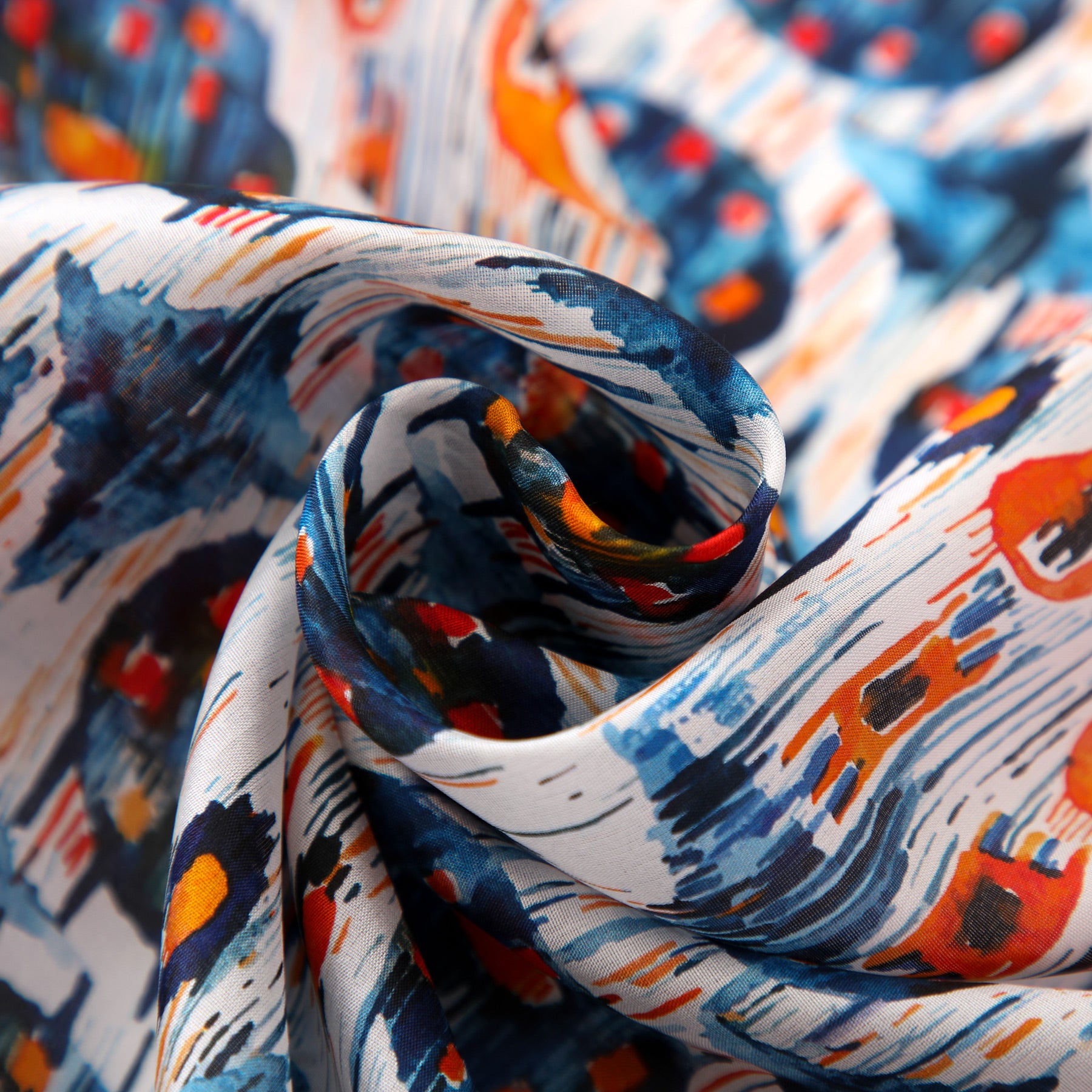 Close-up of the White and Blue Habotai Silk Scarf Ikat Print, featuring swirling folds and a dynamic abstract Ikat-inspired design with blue, orange, and white brushstroke patterns for a textured, vibrant look.