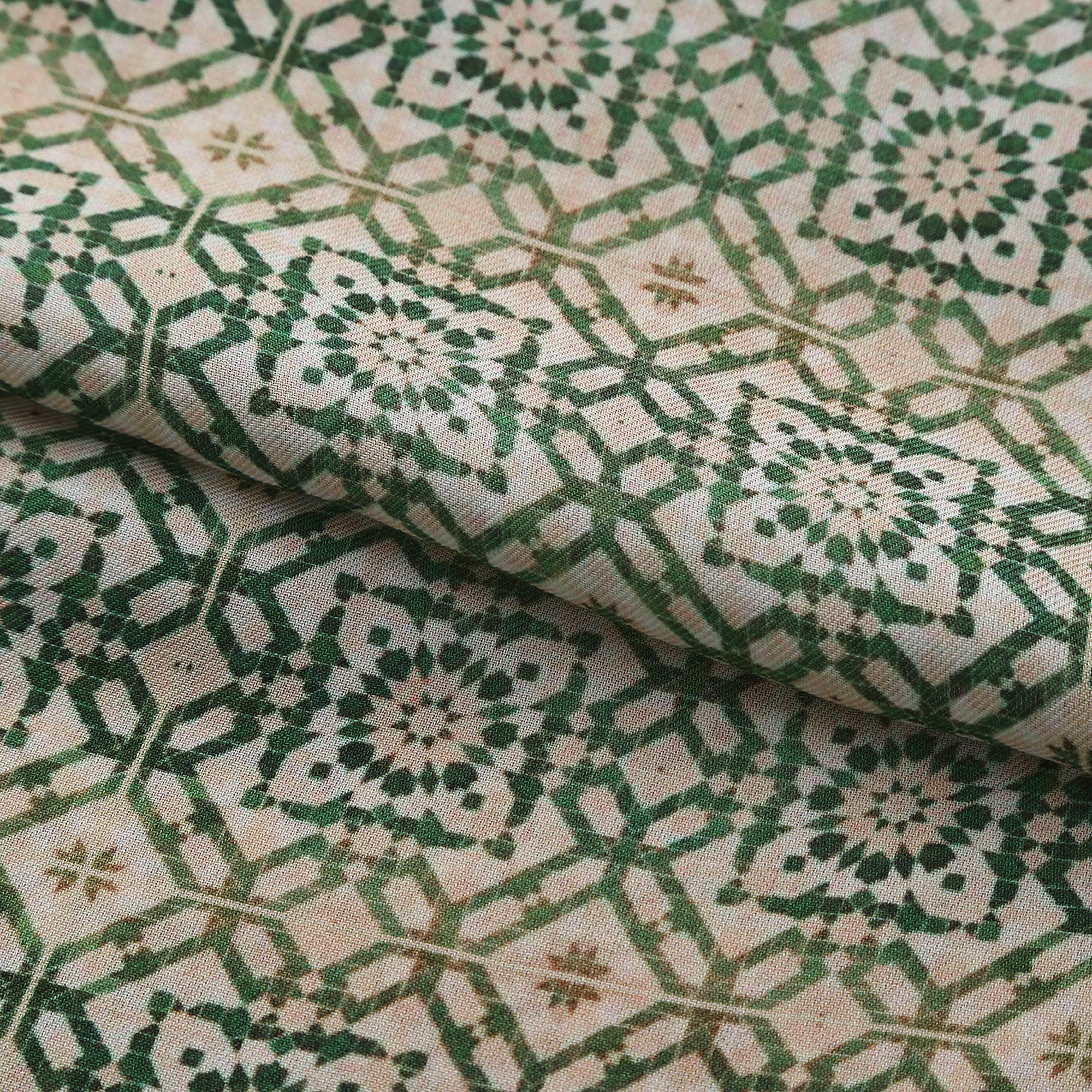 Folded fabric detail of the Green Modal Scarf Alhambra Lattice Azahar, showing the green lattice and the mustard and terracotta border