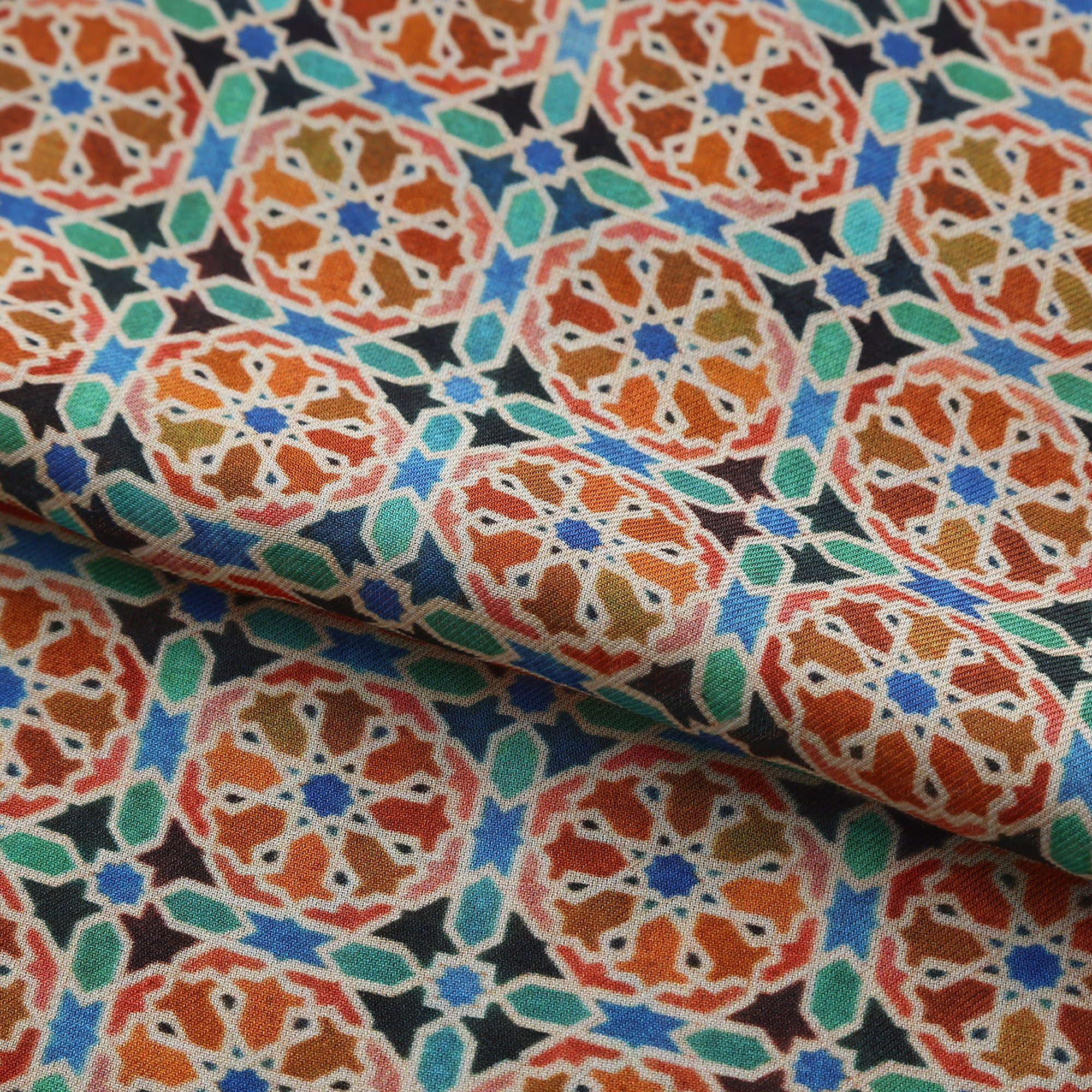 Folded fabric detail of the Orange Modal Scarf Mosaic Wheels Wallada, showing the orange wheels and turquoise fill on black
