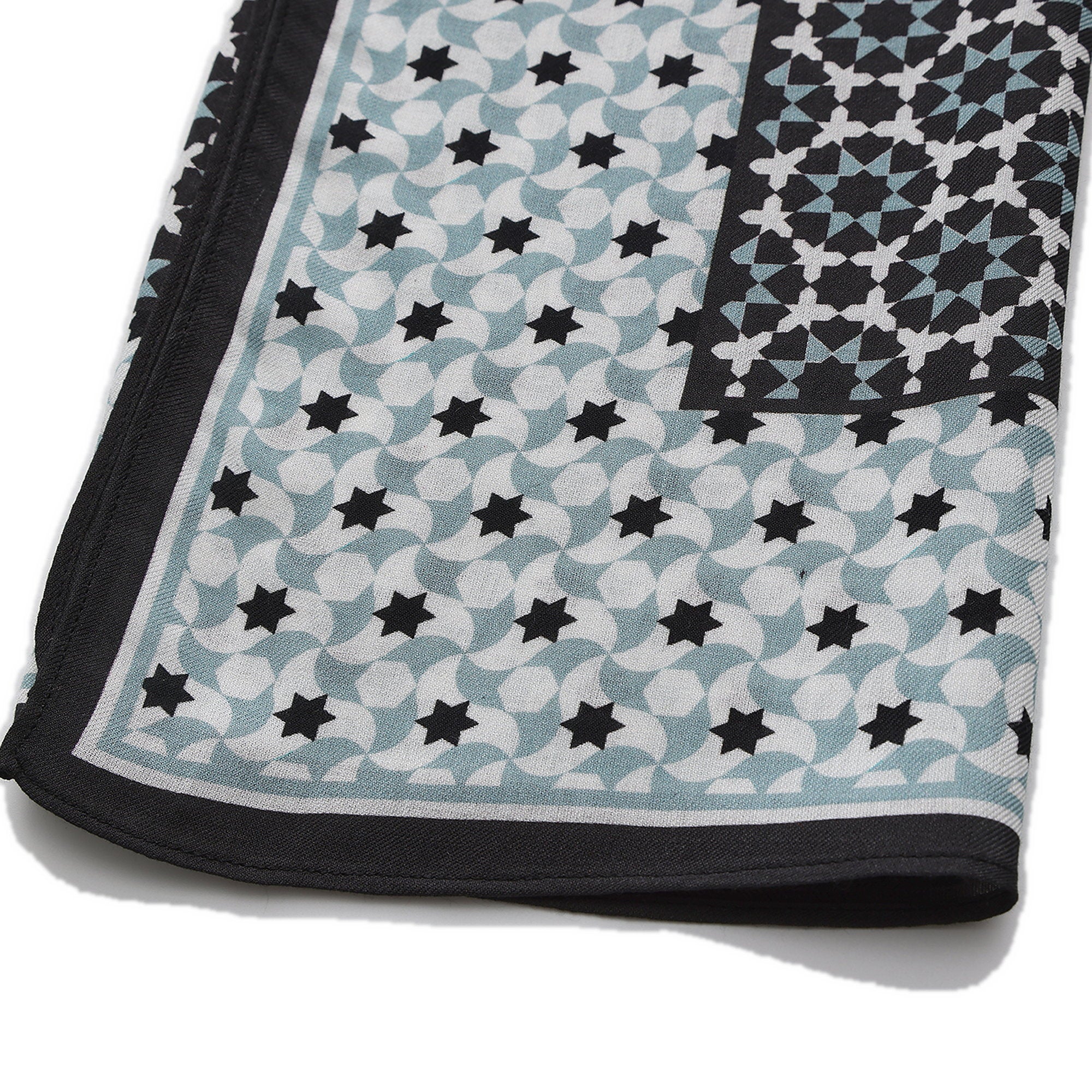 Folded corner of the Black and Grey Modal Scarf Star Lattice Zoraida, showing the border and the hem