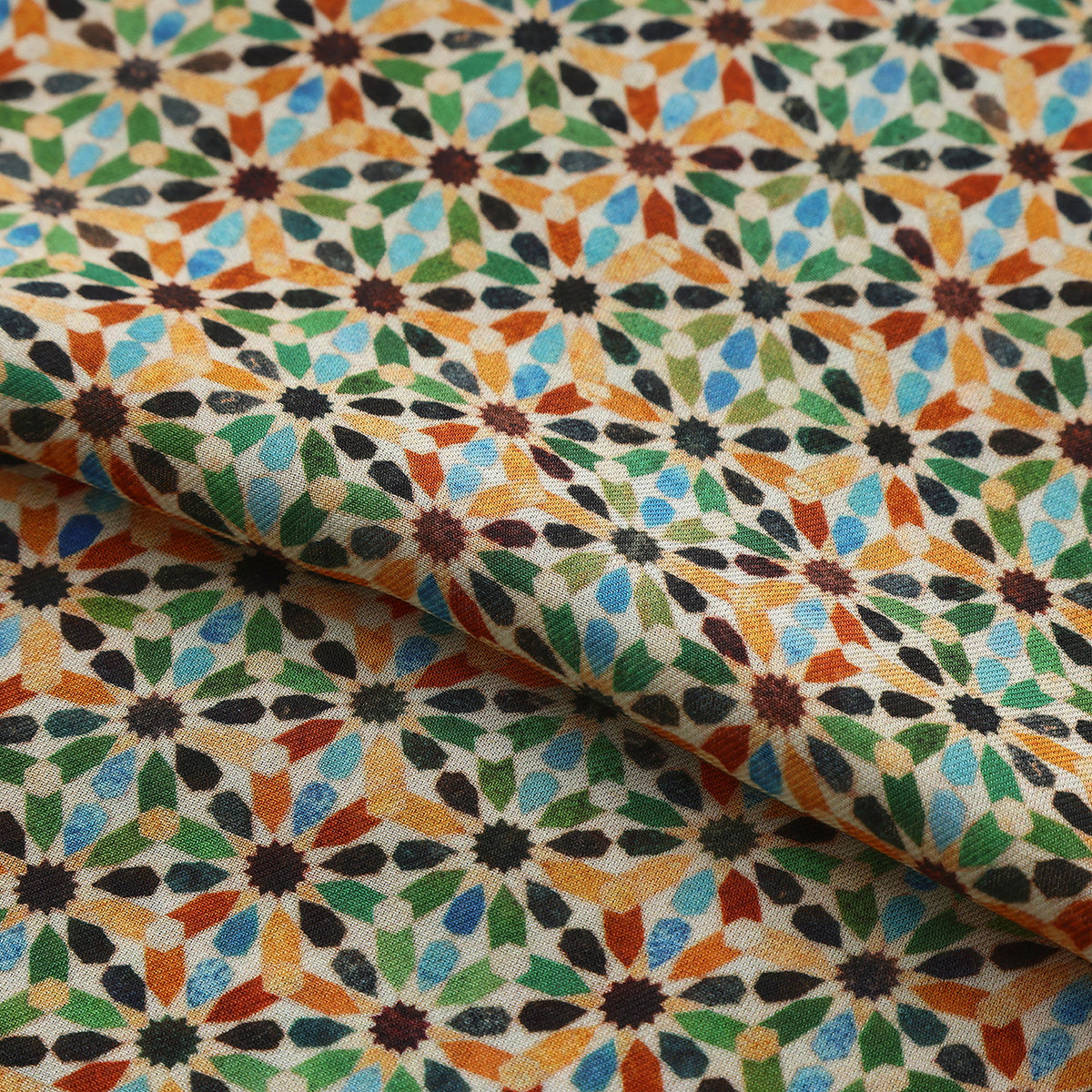Folded fabric detail of the Multicolor Modal Scarf Alhambra Stars Naima, showing the multicolour eight-pointed stars on cream