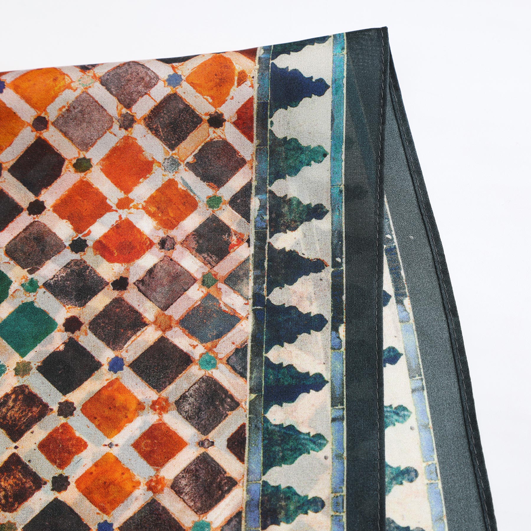 The Colorful Square Scarf Comares, inspired by Alhambra prints, showcases orange, brown, and teal diamond patterns with blue and white borders, displayed flat on a white background.