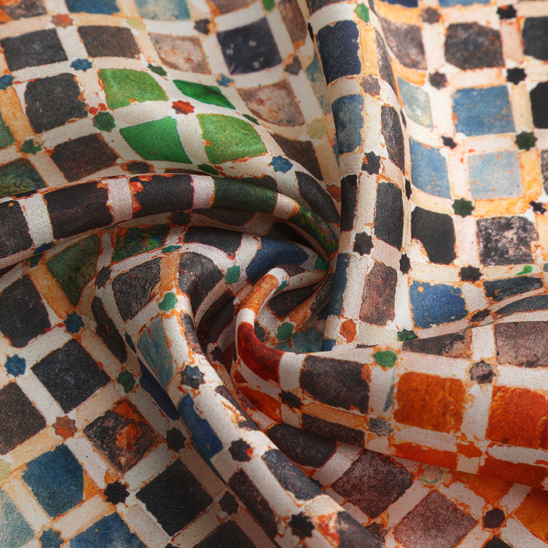 A close-up of the Colorful Square Scarf Comares, featuring a vibrant geometric grid of blue, green, orange, and white squares inspired by Islamic art, with the silk fabric softly gathered in flowing folds.