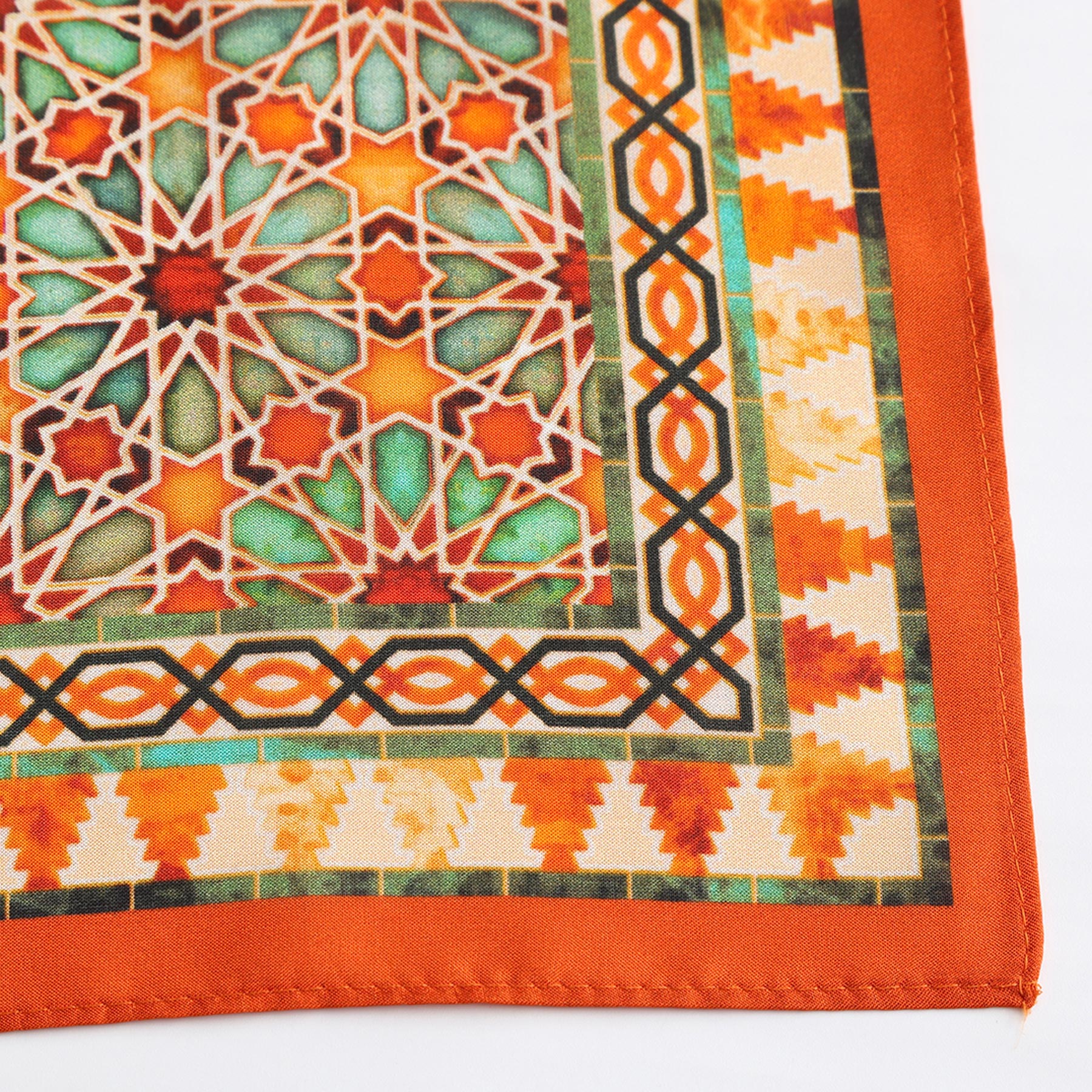 A close-up of the Orange Square Scarf Zellige shows its intricate Islamic art-inspired geometric pattern in orange, red, green, and beige tones with a vibrant orange border and a striking mosaic ornamental style.