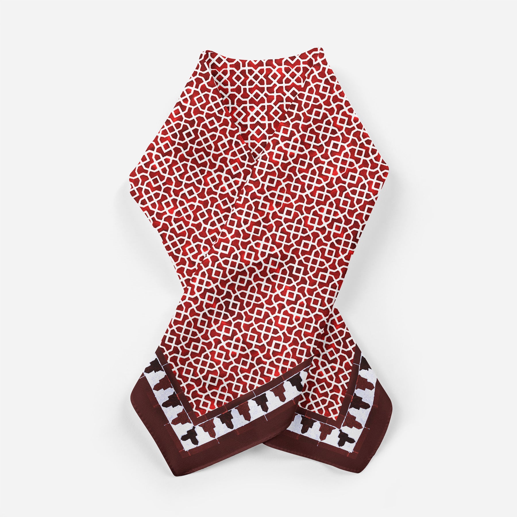 A Red Square Scarf 100% Silk, featuring a red and white geometric pattern inspired by Islamic art and a deep red border with small white and brown shapes, is laid flat on a plain white background.