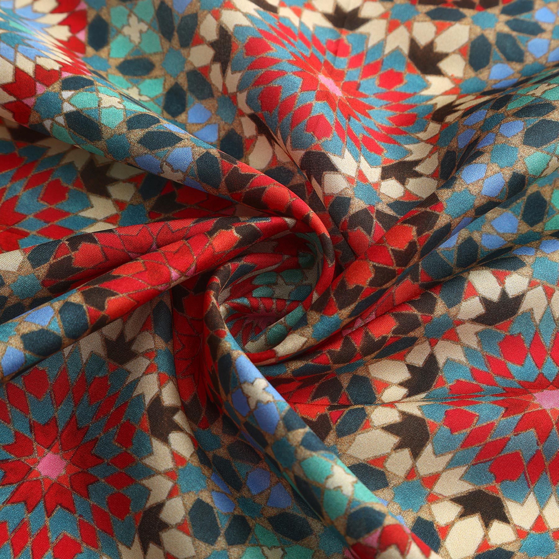 A close-up of the Colorful Silk Neckerchief, featuring intricate geometric patterns in red, blue, teal, beige, and black—twisted at the center for added texture—reflecting Islamic art and Spanish craftsmanship.