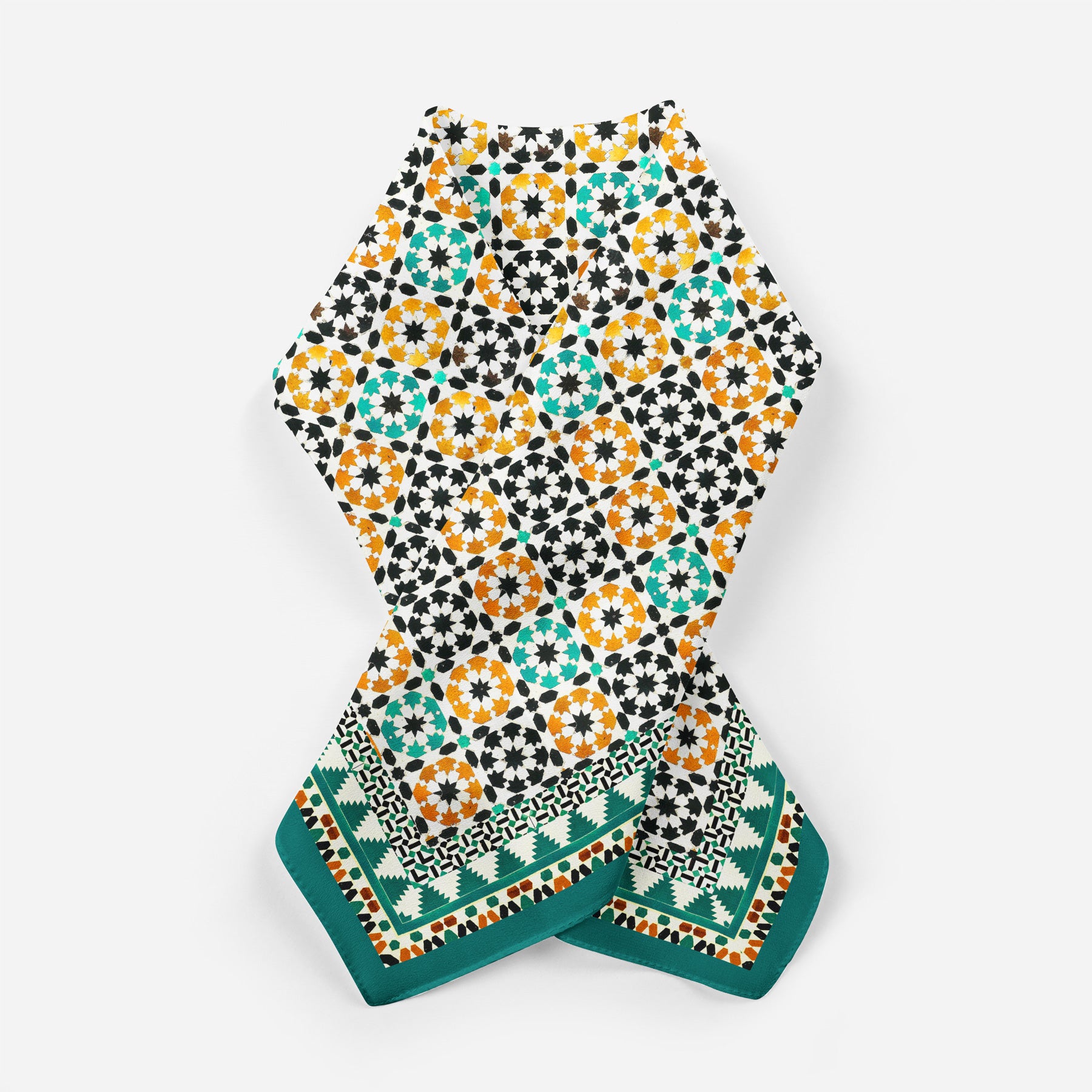 The Green Square Silk Scarf Sabika features intricate geometric patterns inspired by Islamic art in orange, teal, black, and white, with a teal geometric border. The scarf is displayed flat against a white background.