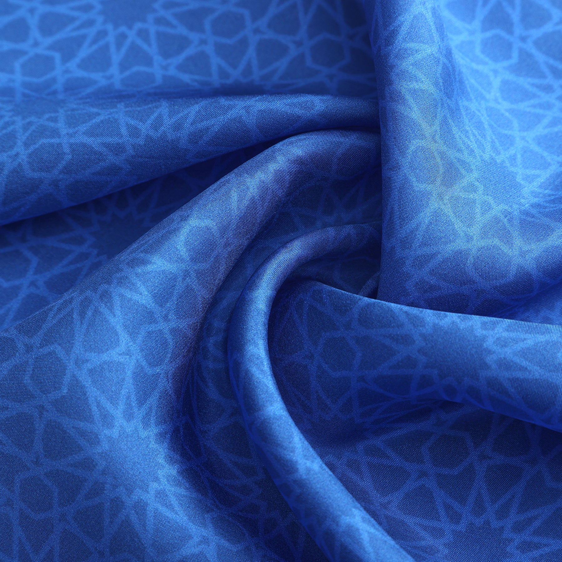 A close-up of the Blue Square Silk Scarf Dalila v1 shows soft folds and a smooth texture, with a subtle Islamic art-inspired geometric pattern of interlocking lines and shapes in light blue against the rich blue fabric.