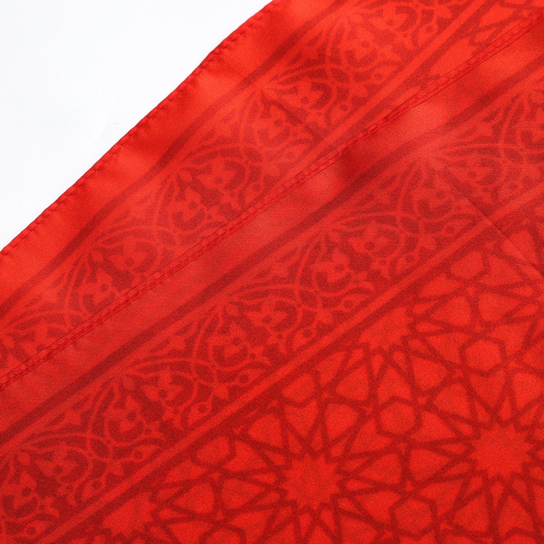Close-up of the Red Square Scarf Dalila v2, crafted from 100% silk, showcasing intricate geometric and floral patterns inspired by Islamic art with neatly stitched edges.