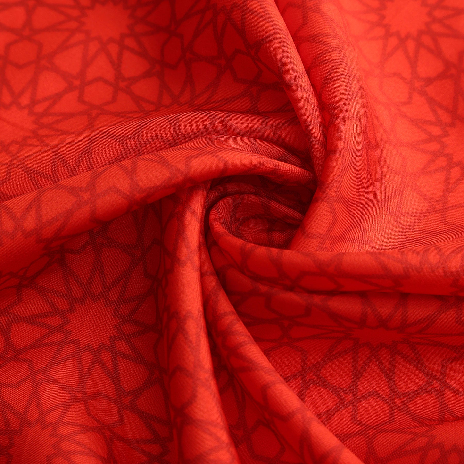 A close-up of the Red Square Scarf Dalila v2, crafted from 100% silk, displays its intricate geometric pattern inspired by Islamic art, with soft folds and a swirling texture at the gathered center.