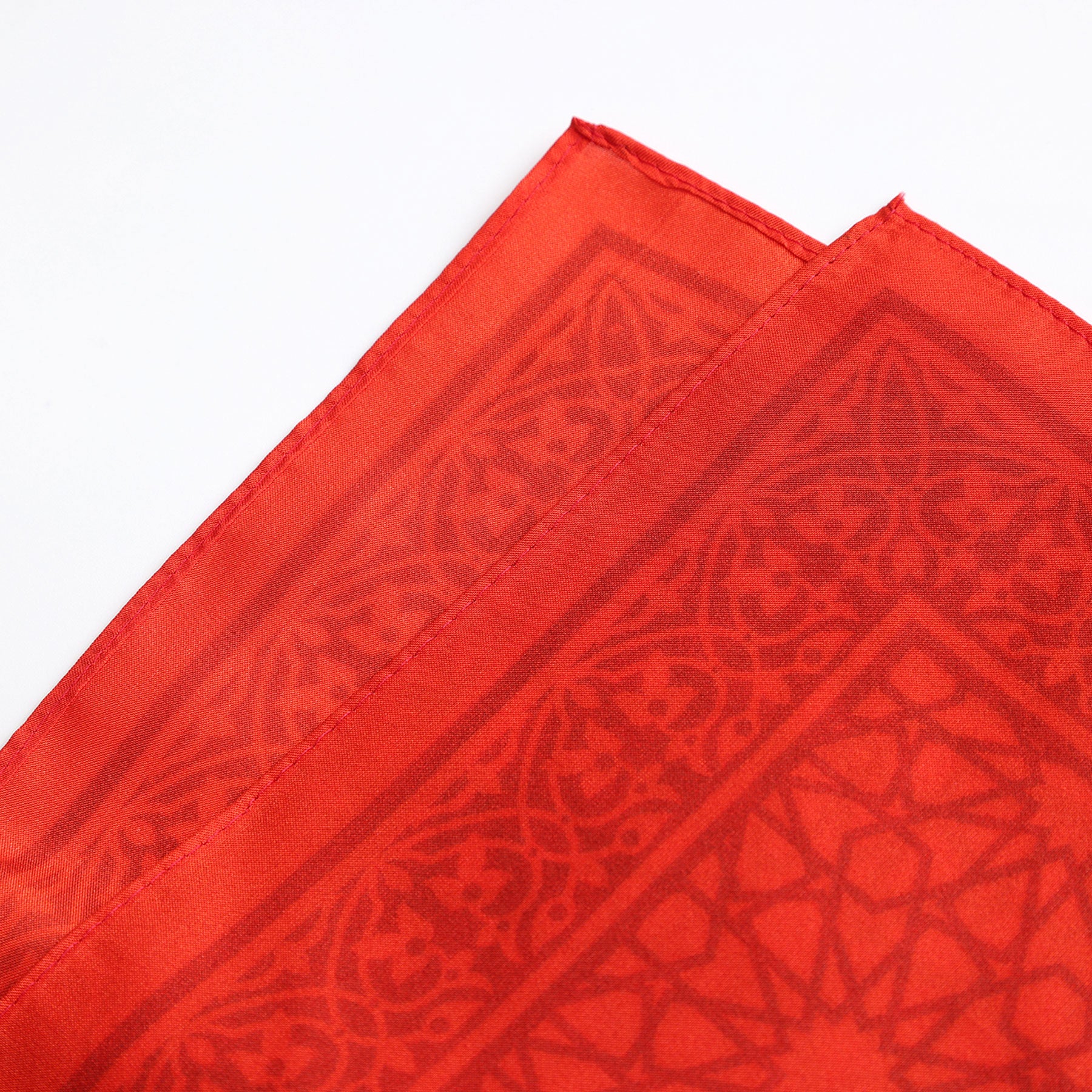 A close-up of two folded Red Square Scarf Dalila v2, crafted from 100% silk with intricate geometric patterns inspired by Islamic art and fine edge stitching, displayed on a white background.